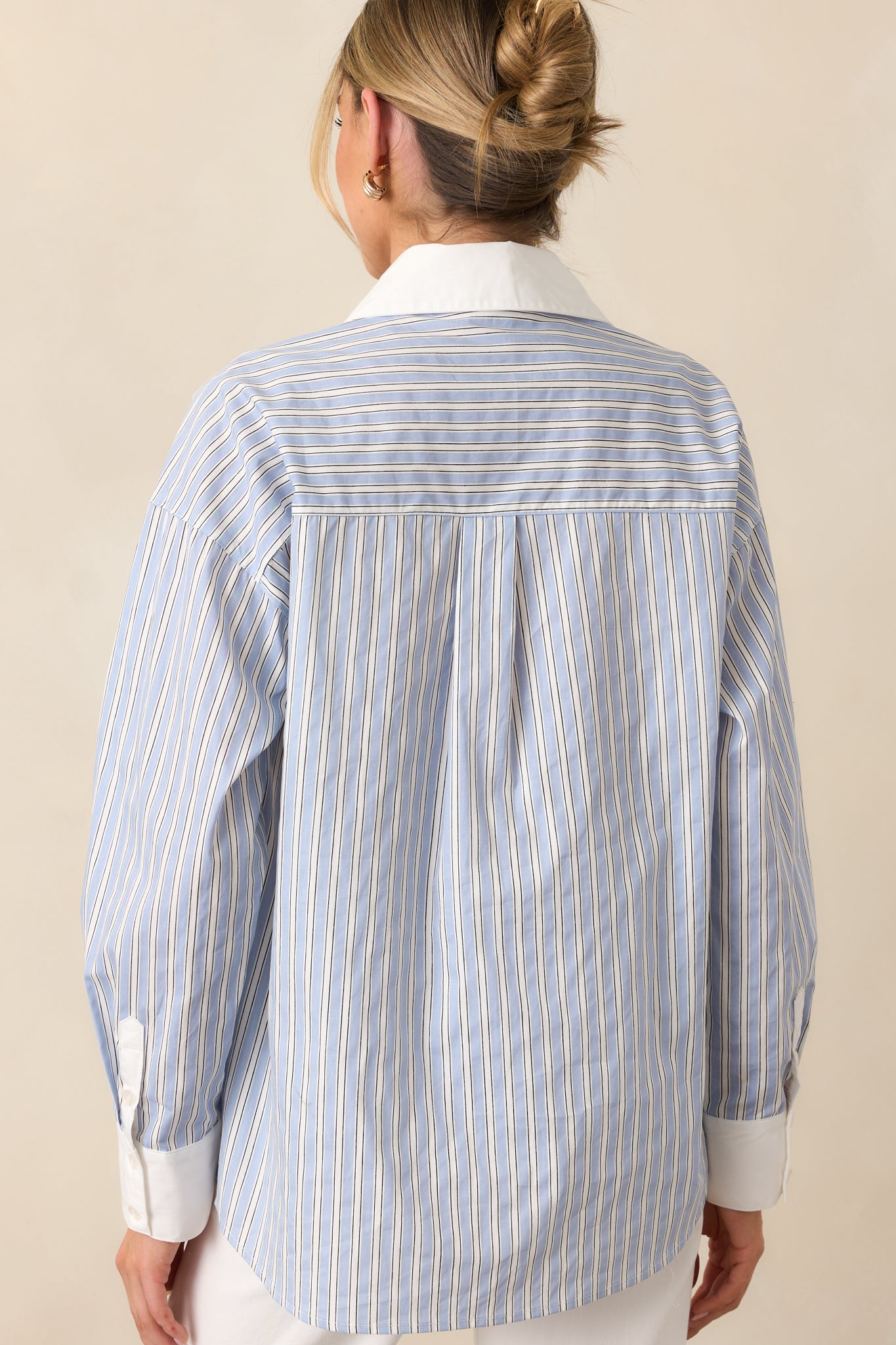 The back of this blue blouse offers a simple, clean design with a relaxed fit and subtle stripe pattern.