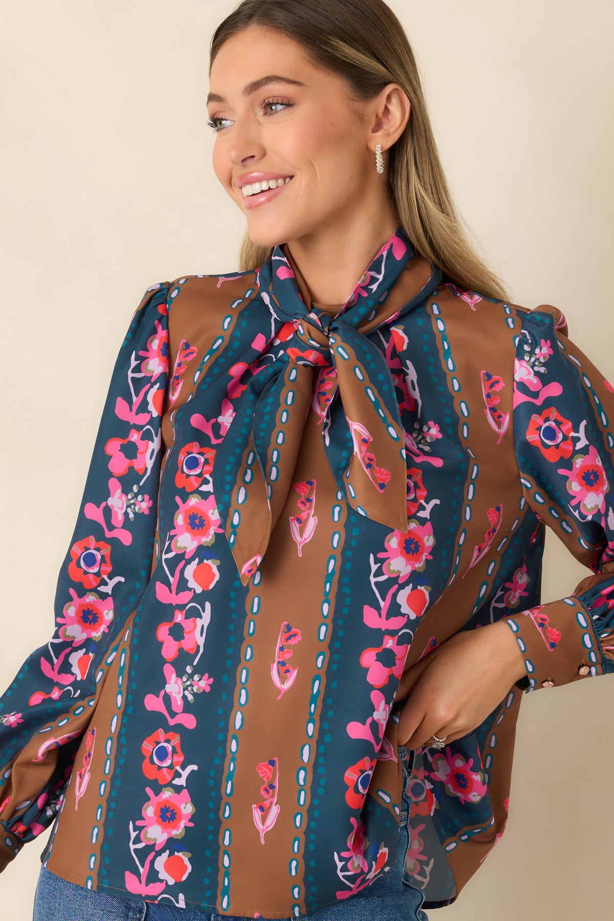 Long sleeves finish with buttoned cuffs on the blue and caramel striped floral top.