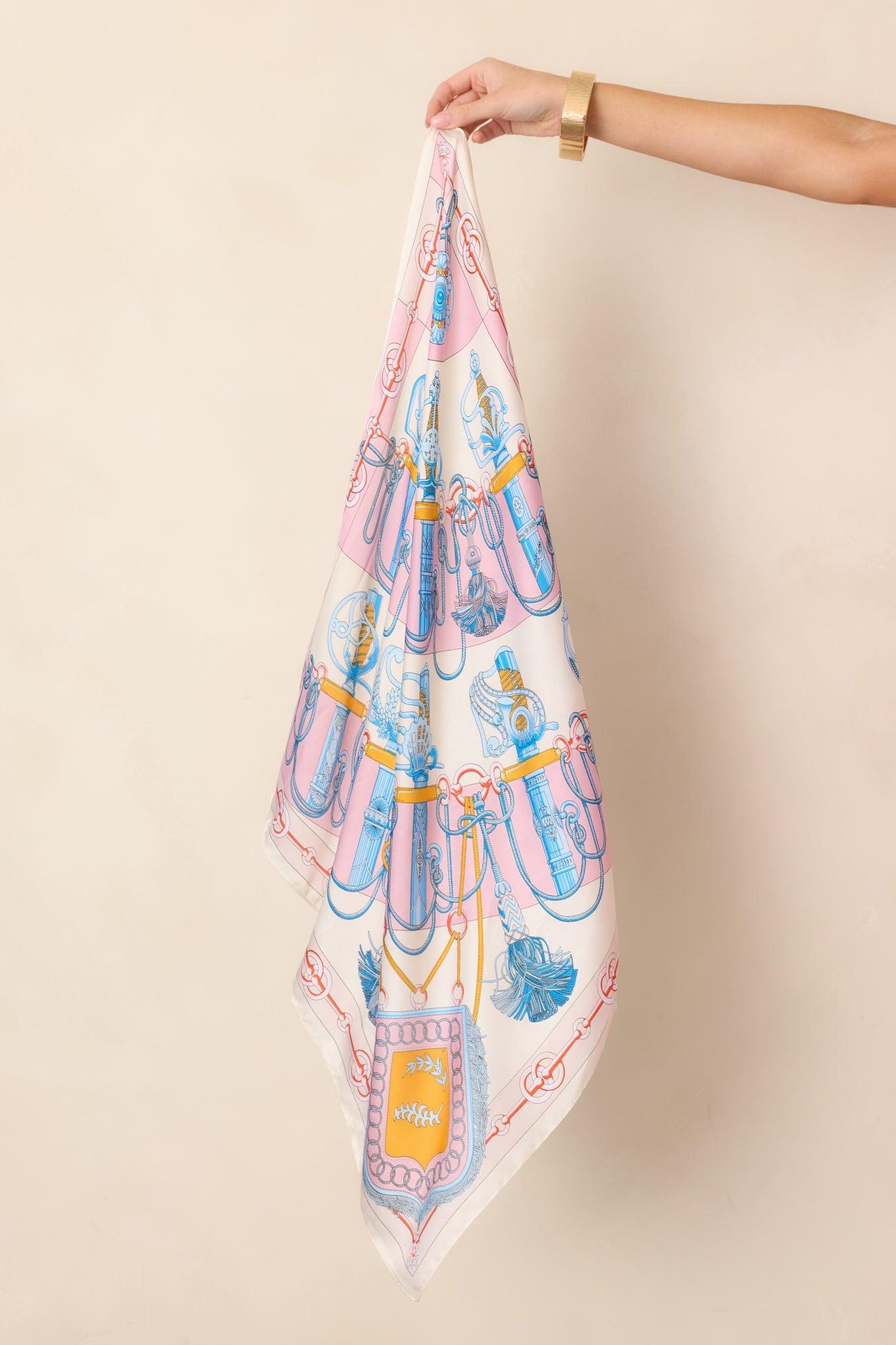 Detailed section of the hair scarf highlighting ornate blue, coral, and gold motifs layered with rope and tassel-inspired artwork.