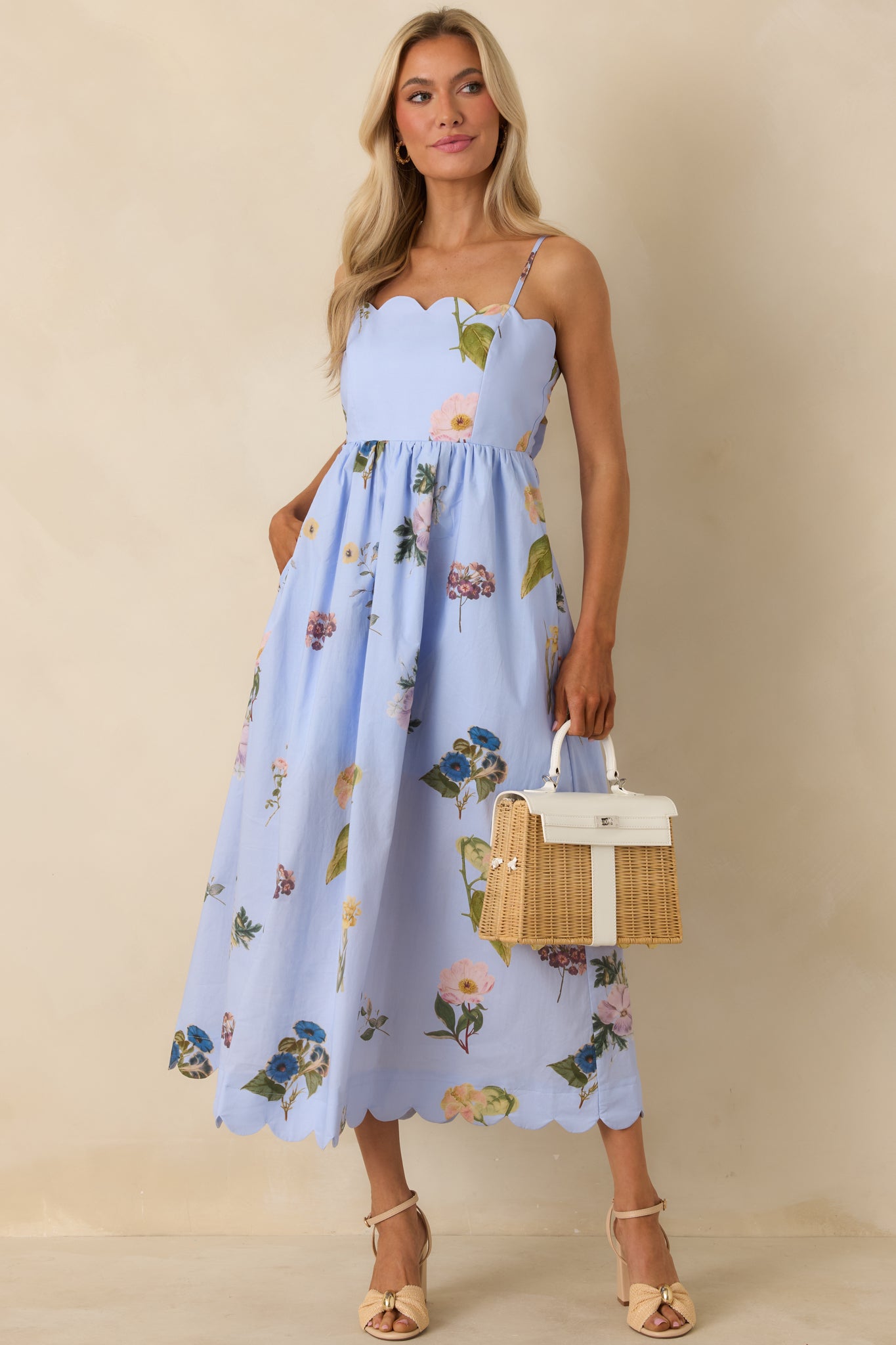 Blue cotton midi dress with multicolor floral print, scalloped neckline, adjustable spaghetti straps, and flowy skirt.