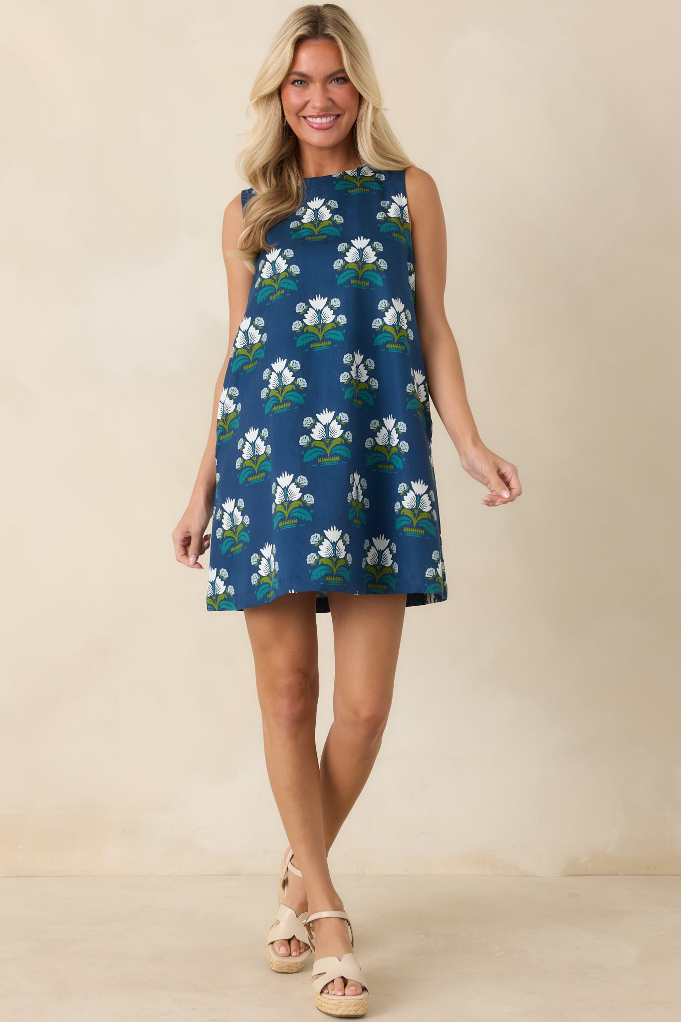 Deep blue cotton mini dress featuring white floral print, teal accents, a round neckline, and relaxed shift silhouette.