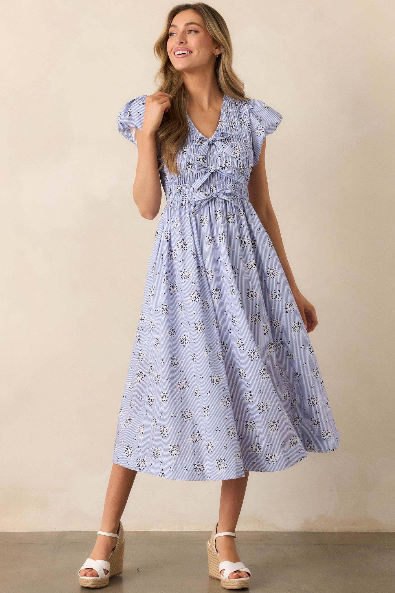 Blue dress styled in a front view, drawing attention to the combination of smocking and bow detailing.