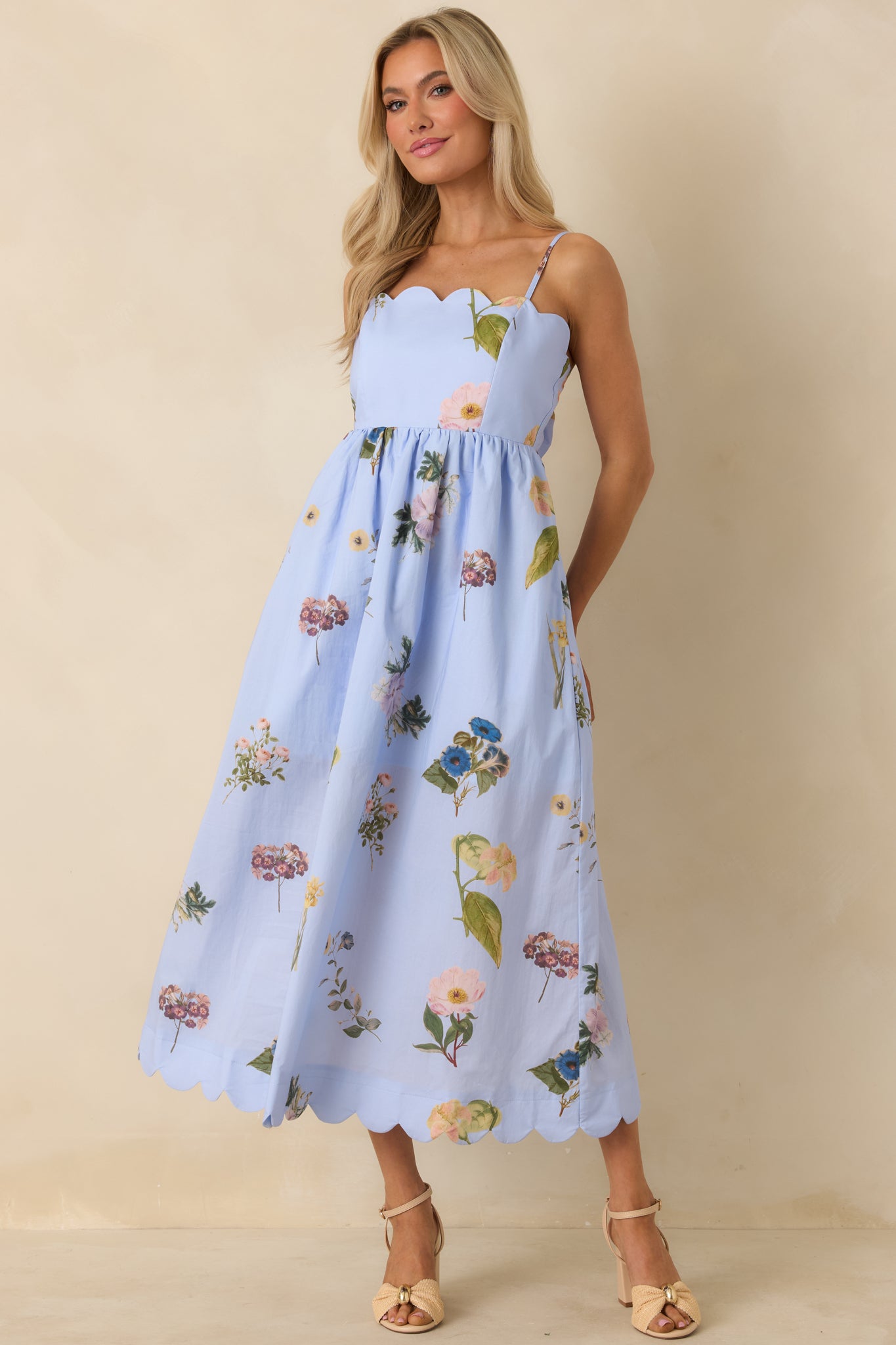 Flowing blue cotton dress with scalloped neckline and hem, fitted bodice, and tie-back accent for a customizable fit.