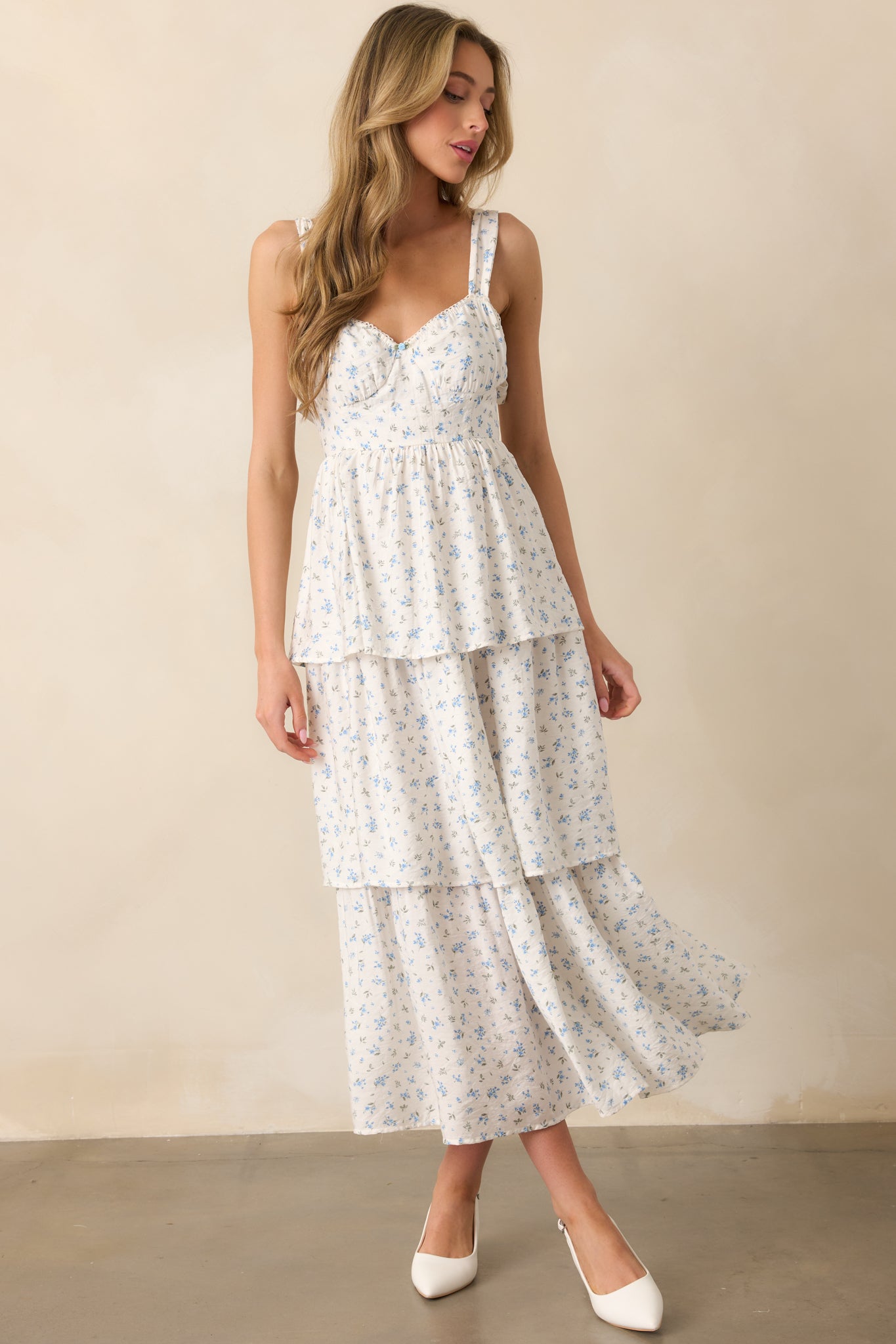 A full-body shot of the blue floral maxi dress, emphasizing the smocked back panel and two back bow details. The tiered skirt and elastic sweetheart neckline complete the elegant design.