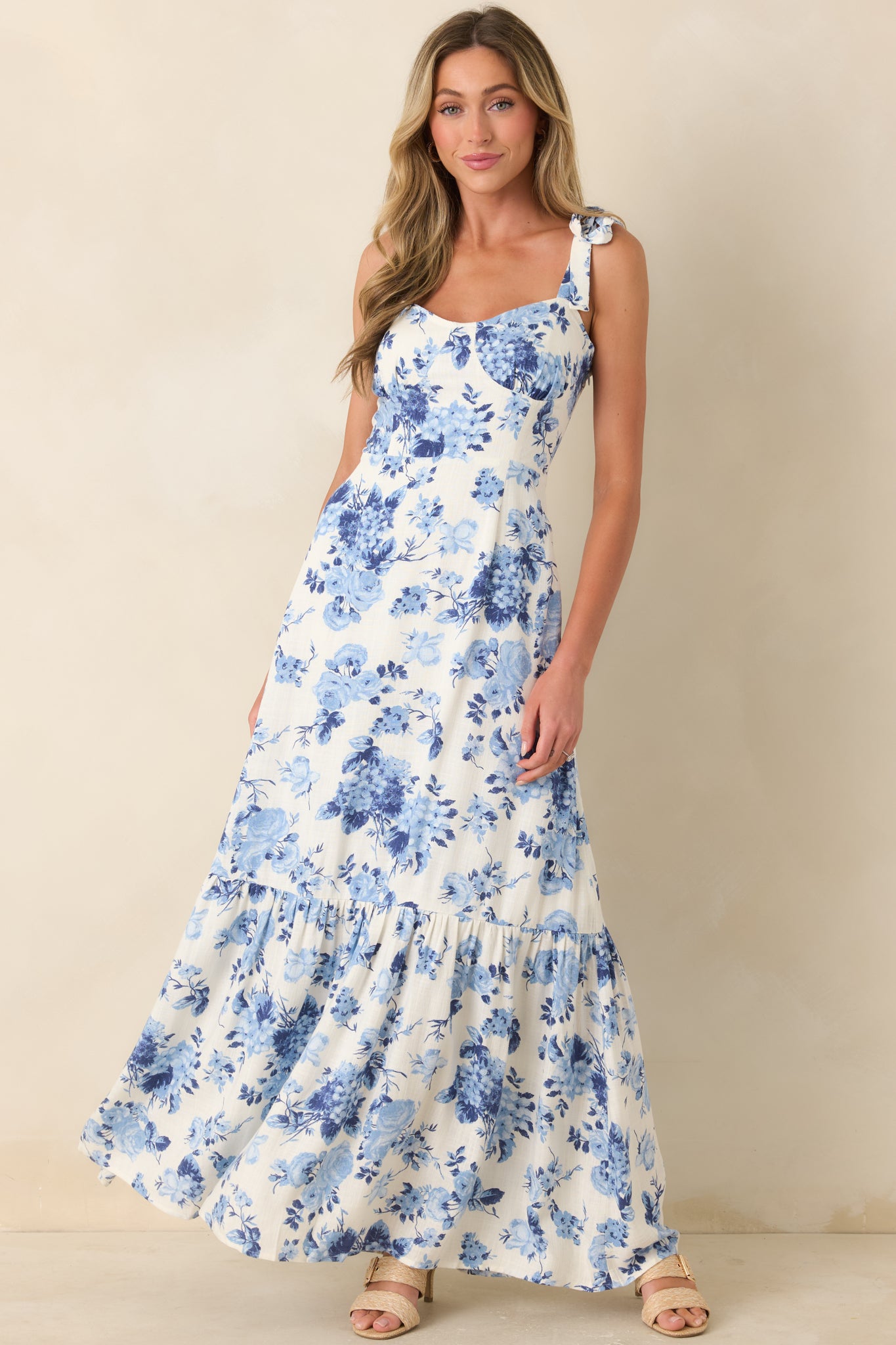 Blue floral midi dress with ivory base, tie-shoulder straps, and tiered skirt.