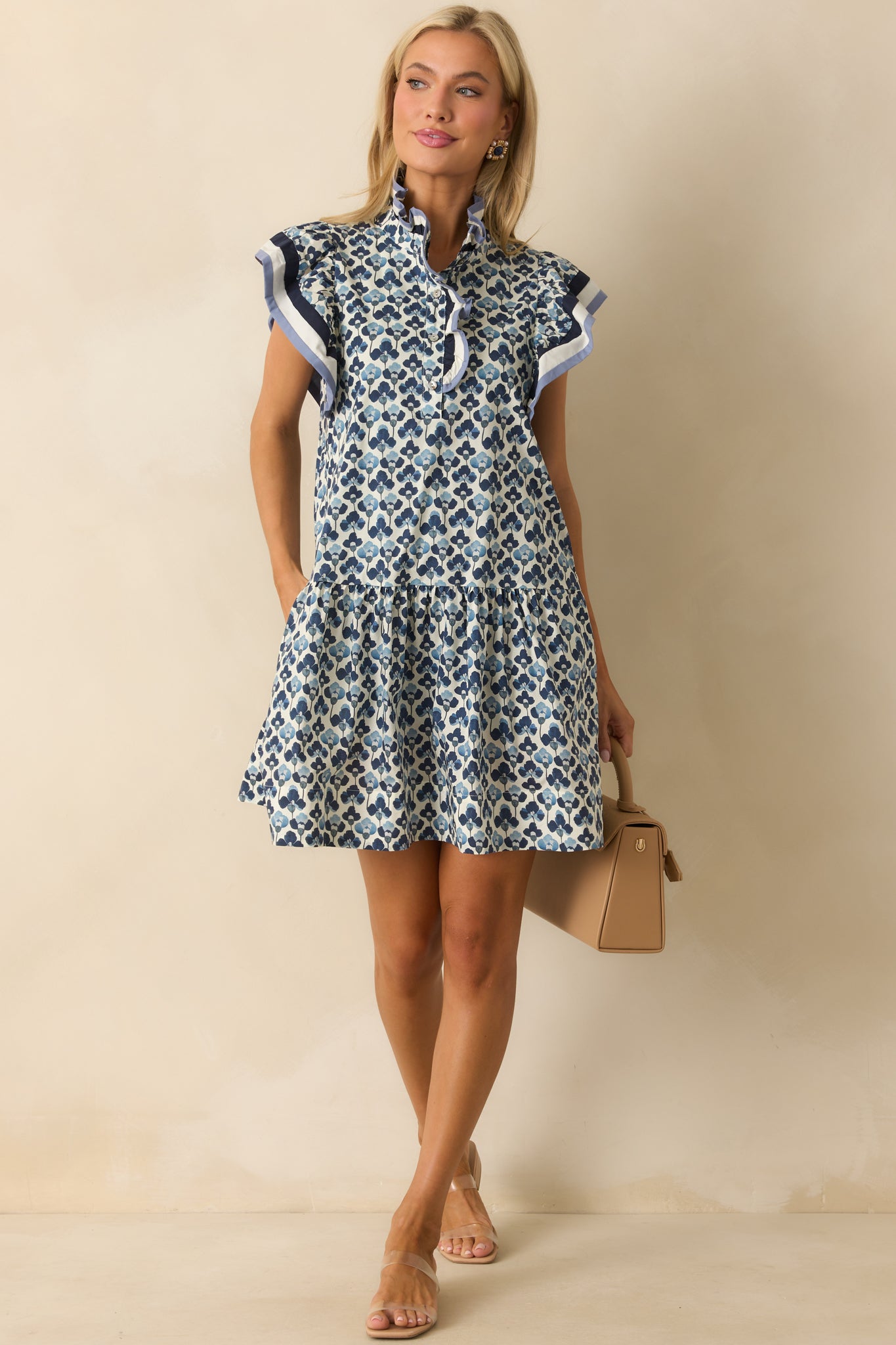 Full view of the blue floral mini dress with ruffle mock neckline and button front closure.