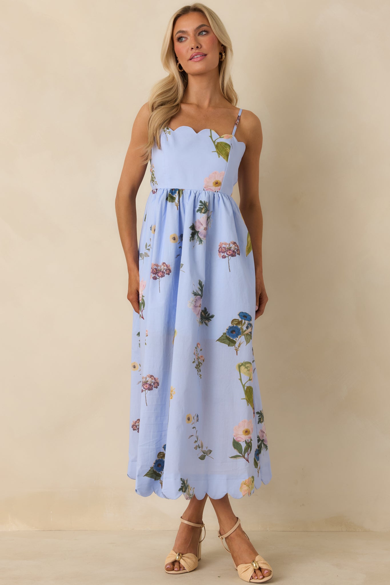 Blue floral print midi dress with spaghetti straps, scalloped edges, and airy skirt for comfortable all-day wear.