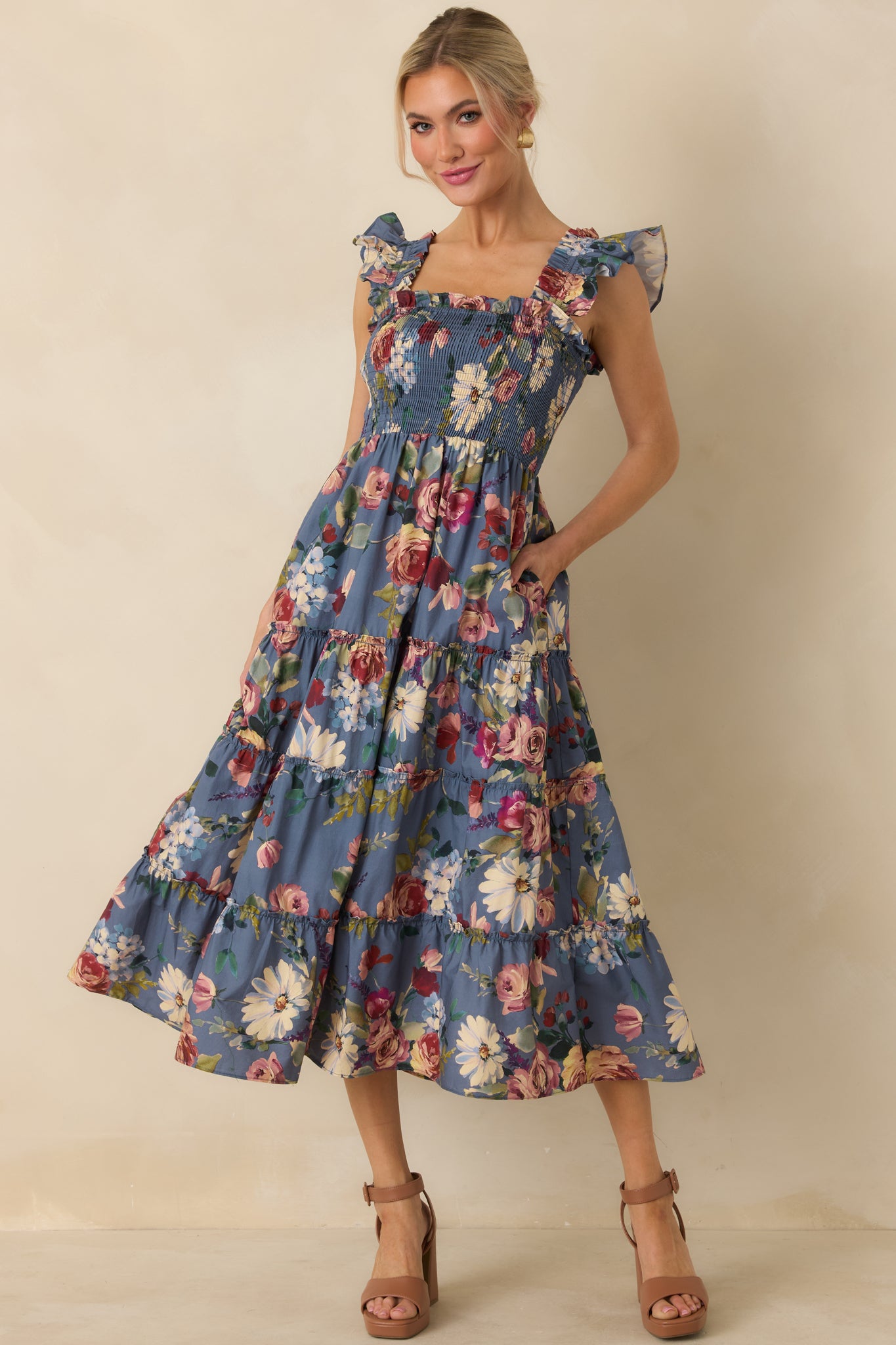 Blue floral cotton midi dress with a smocked bodice, square neckline, ruffled shoulder straps, and voluminous tiered skirt.