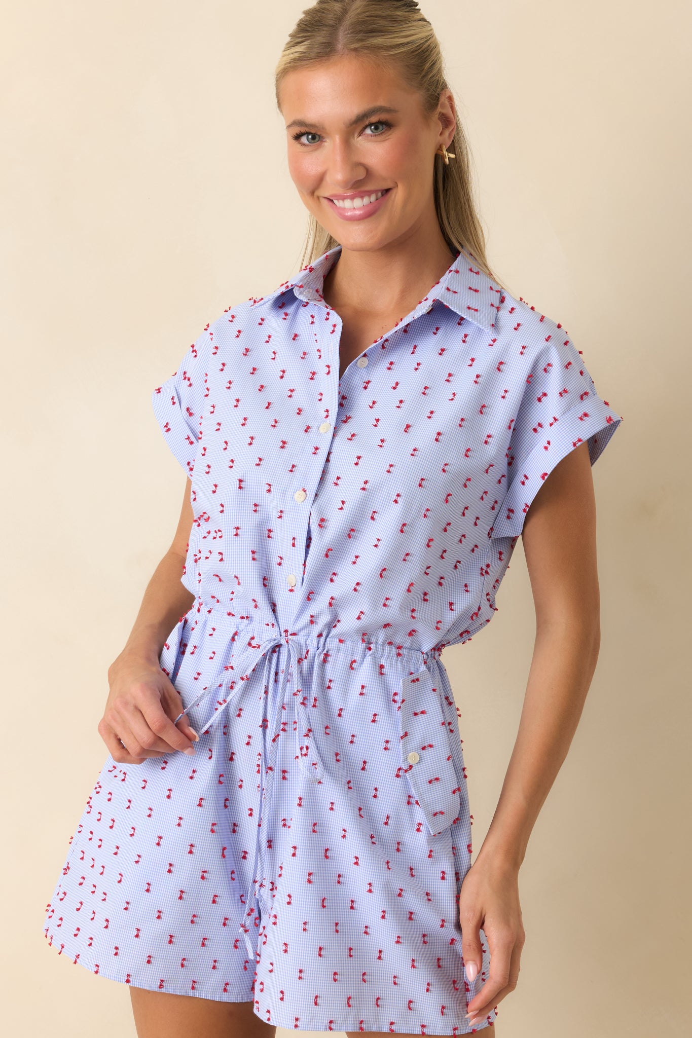 Blue gingham romper highlighting the elastic drawstring waist, side pocket accents, and relaxed shorts design.