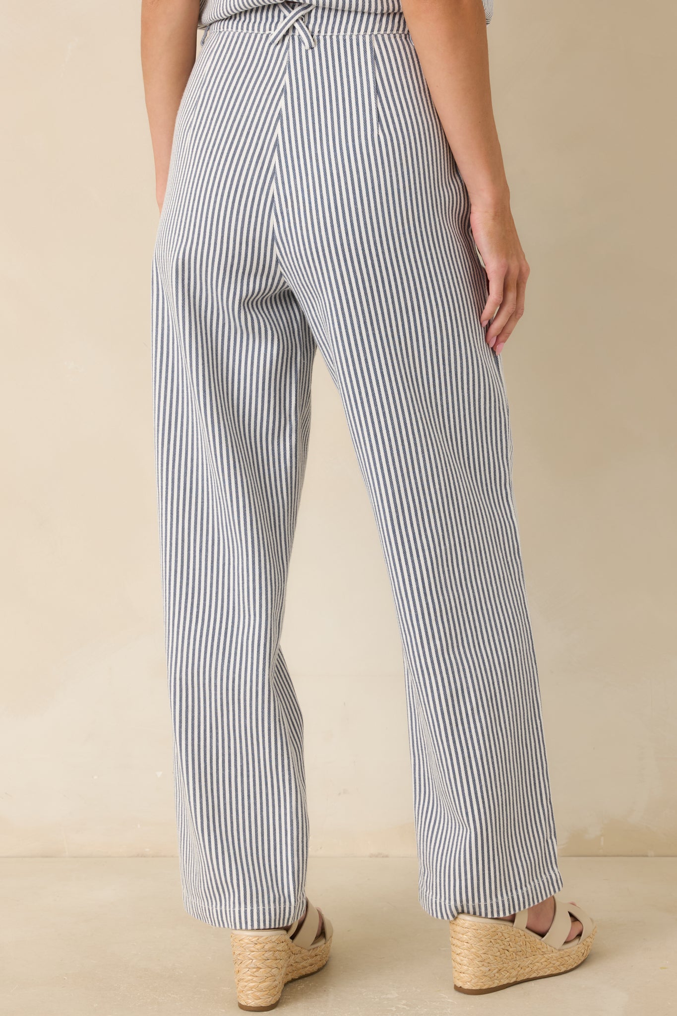 Back view of the blue and ivory striped pants featuring a high-rise fit and flowing wide leg silhouette.