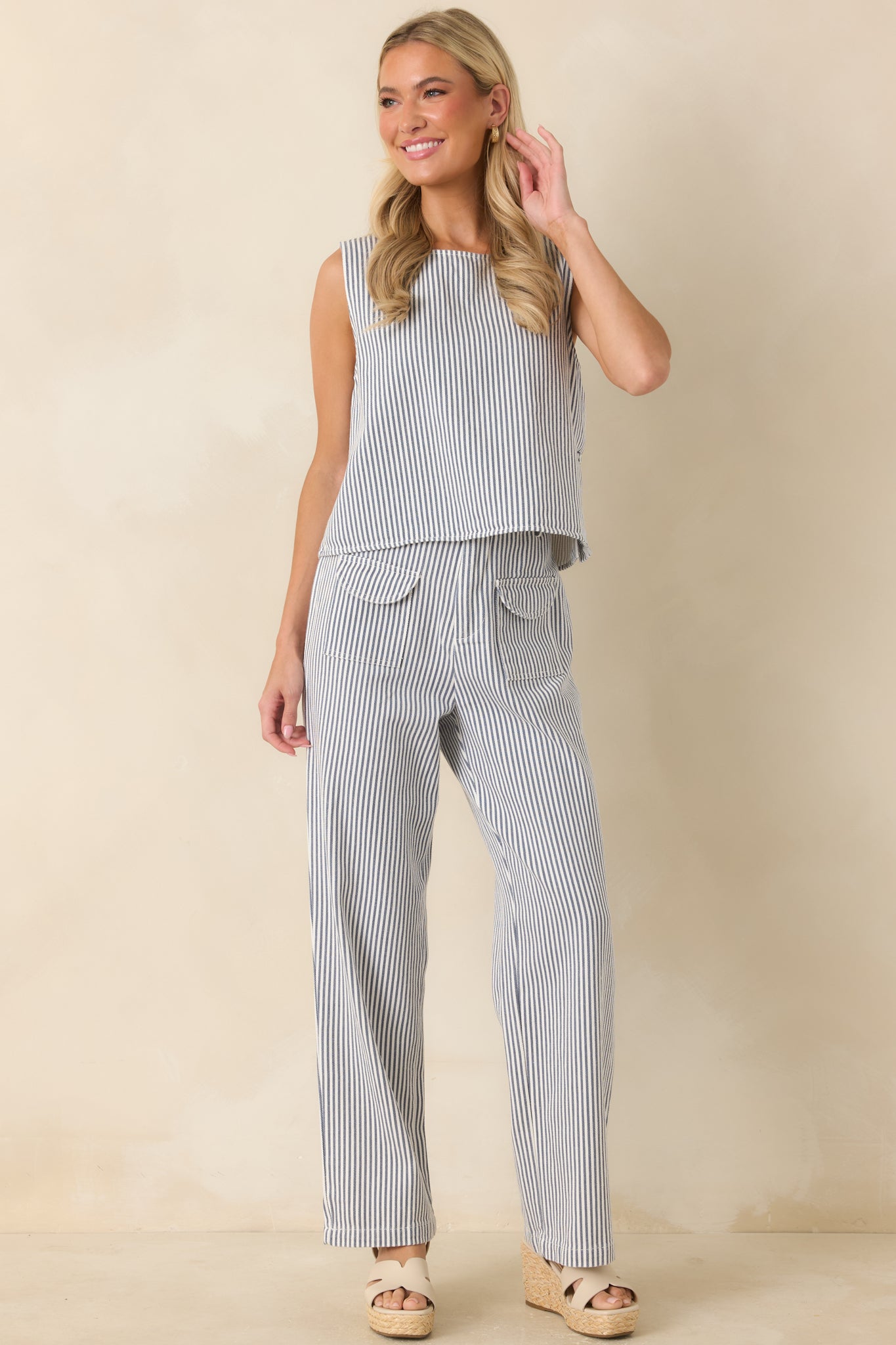 Blue and ivory striped pants featuring a high-rise waist, wide leg silhouette, and front patch pockets with flap detailing.