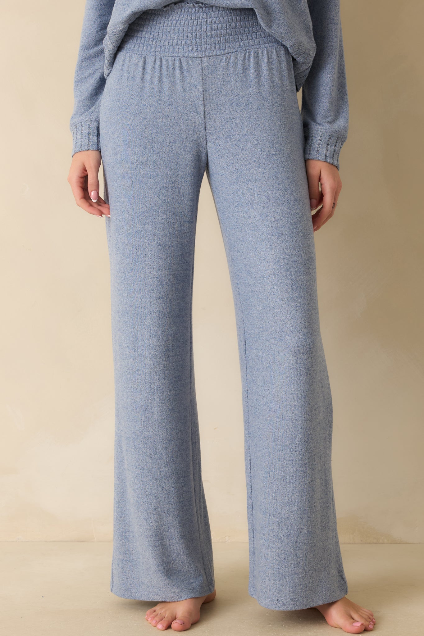 Blue knit pants with high-rise waist, wide-leg silhouette, and relaxed drape over the legs.