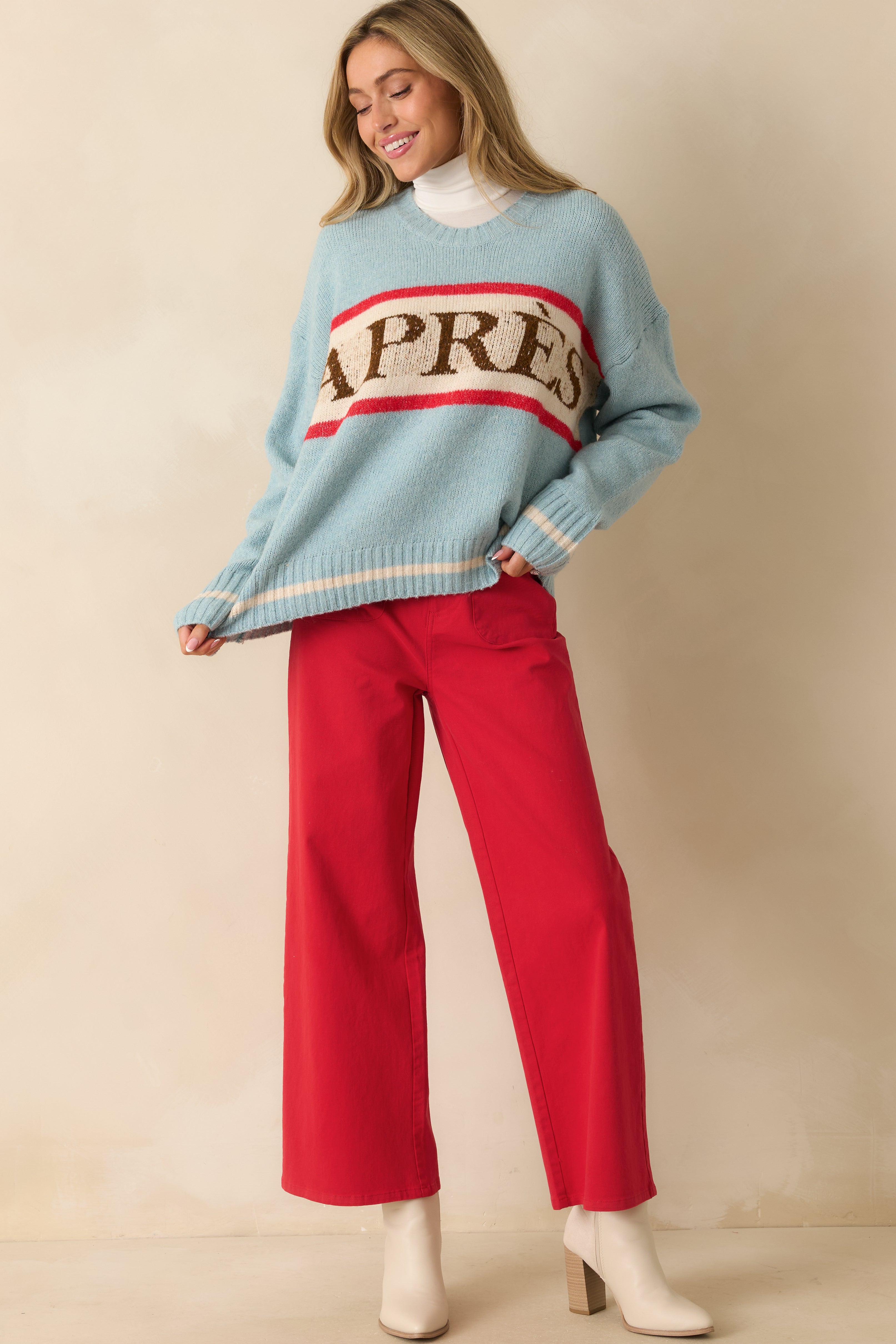 Relaxed soft blue knit pullover with long sleeves, ribbed hem and cuffs, and contrasting red and ivory stripes across the chest.