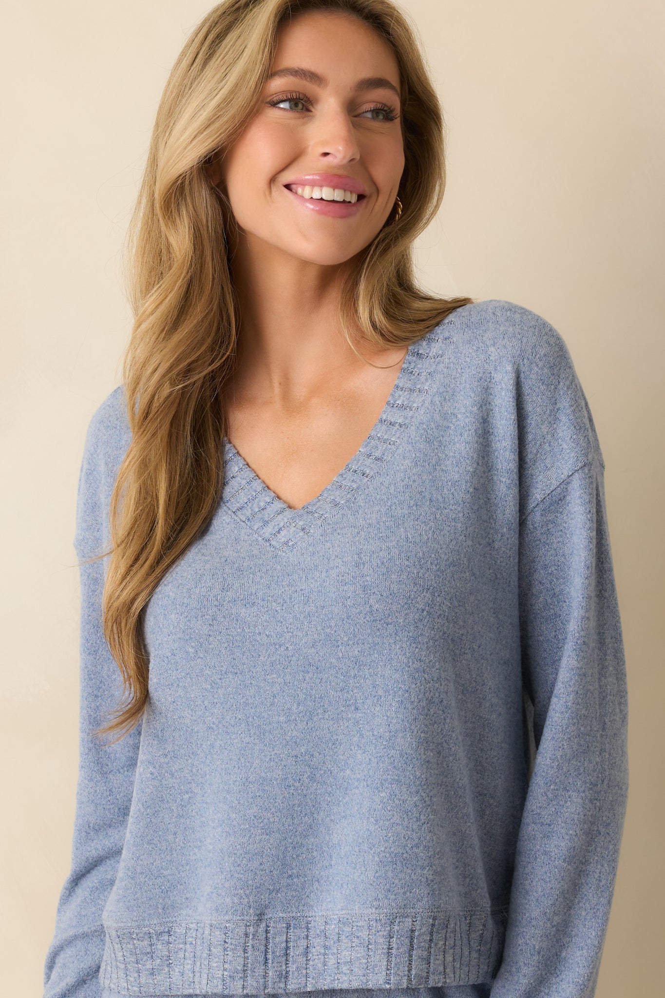 Detailed view of ribbed cuff and smooth knit fabric along the sleeve of the blue sweater.