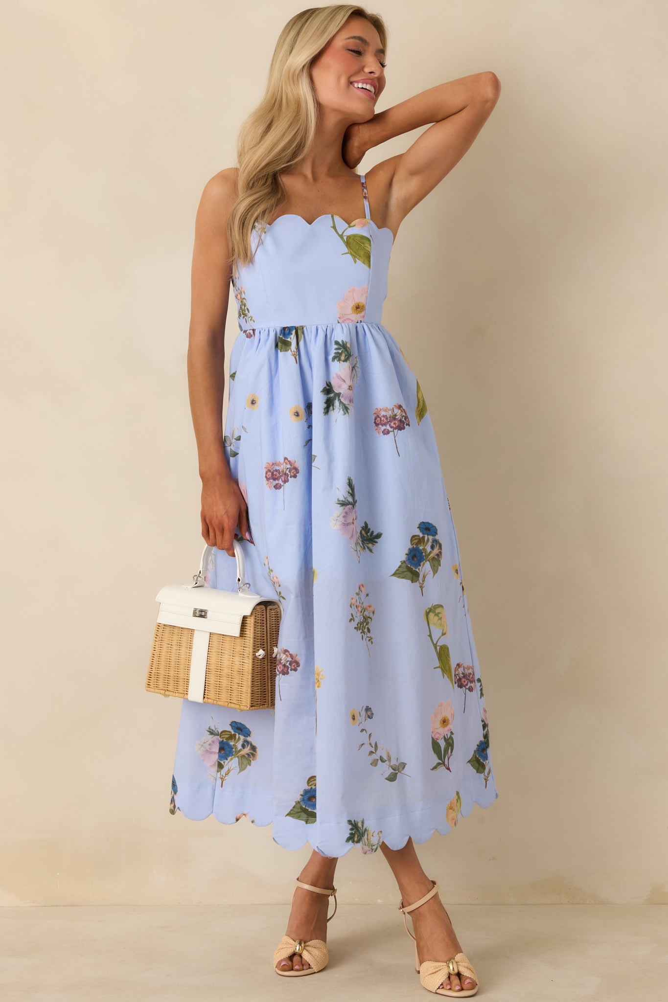 Blue midi dress with colorful floral pattern, adjustable straps, and flowy skirt, highlighting scalloped neckline and lightweight fabric.
