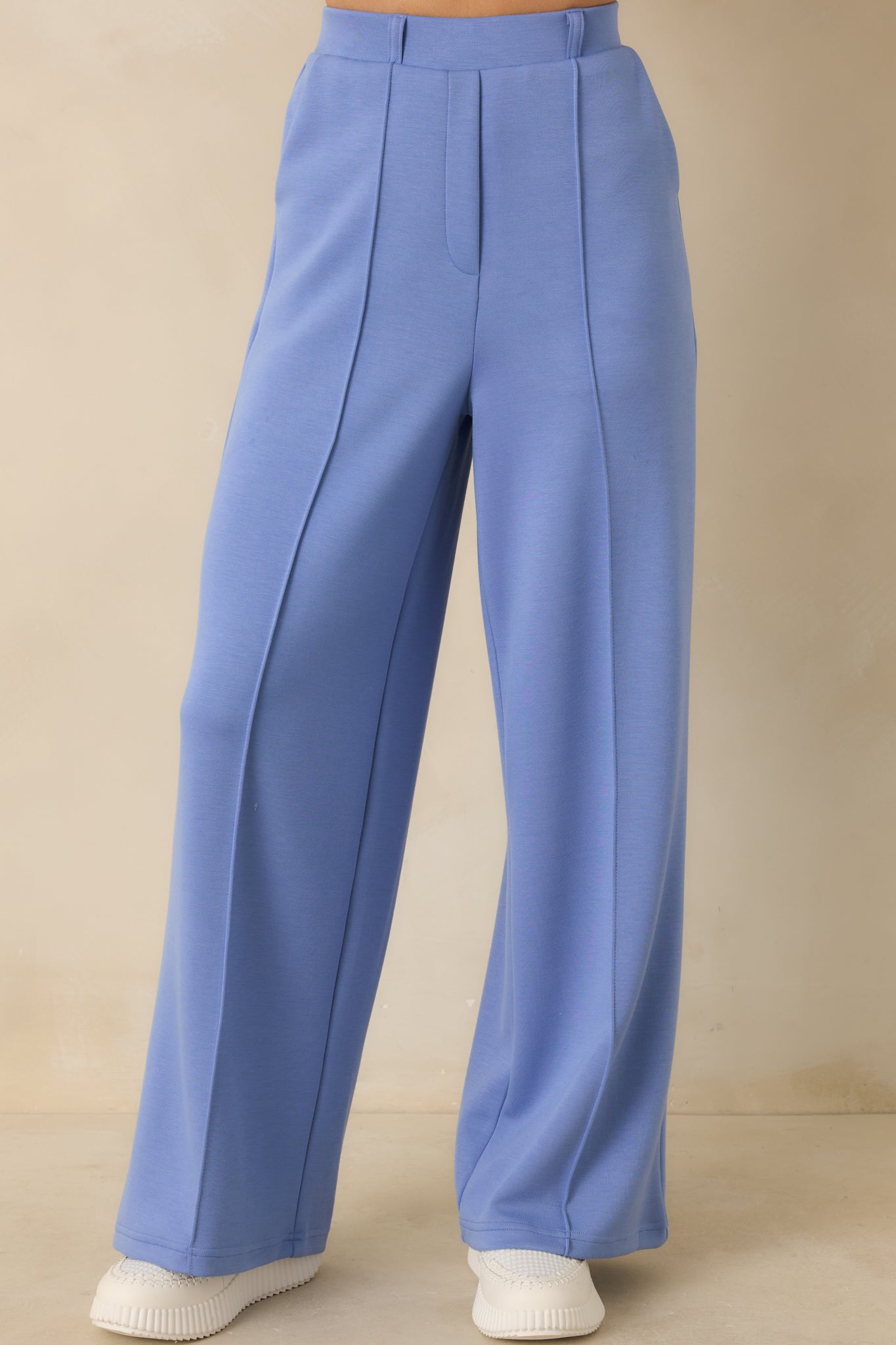 Tailored blue pants emphasizing the smooth knit texture and crisp pleat lines along the front.