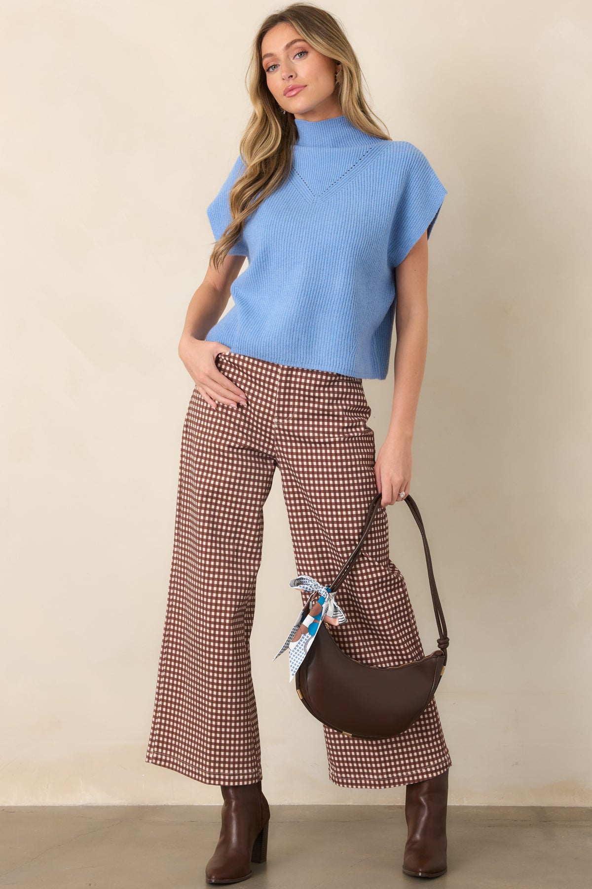 Refined blue sweater showcasing a softly textured ribbed construction, high neckline, short cap sleeves, and relaxed fit.