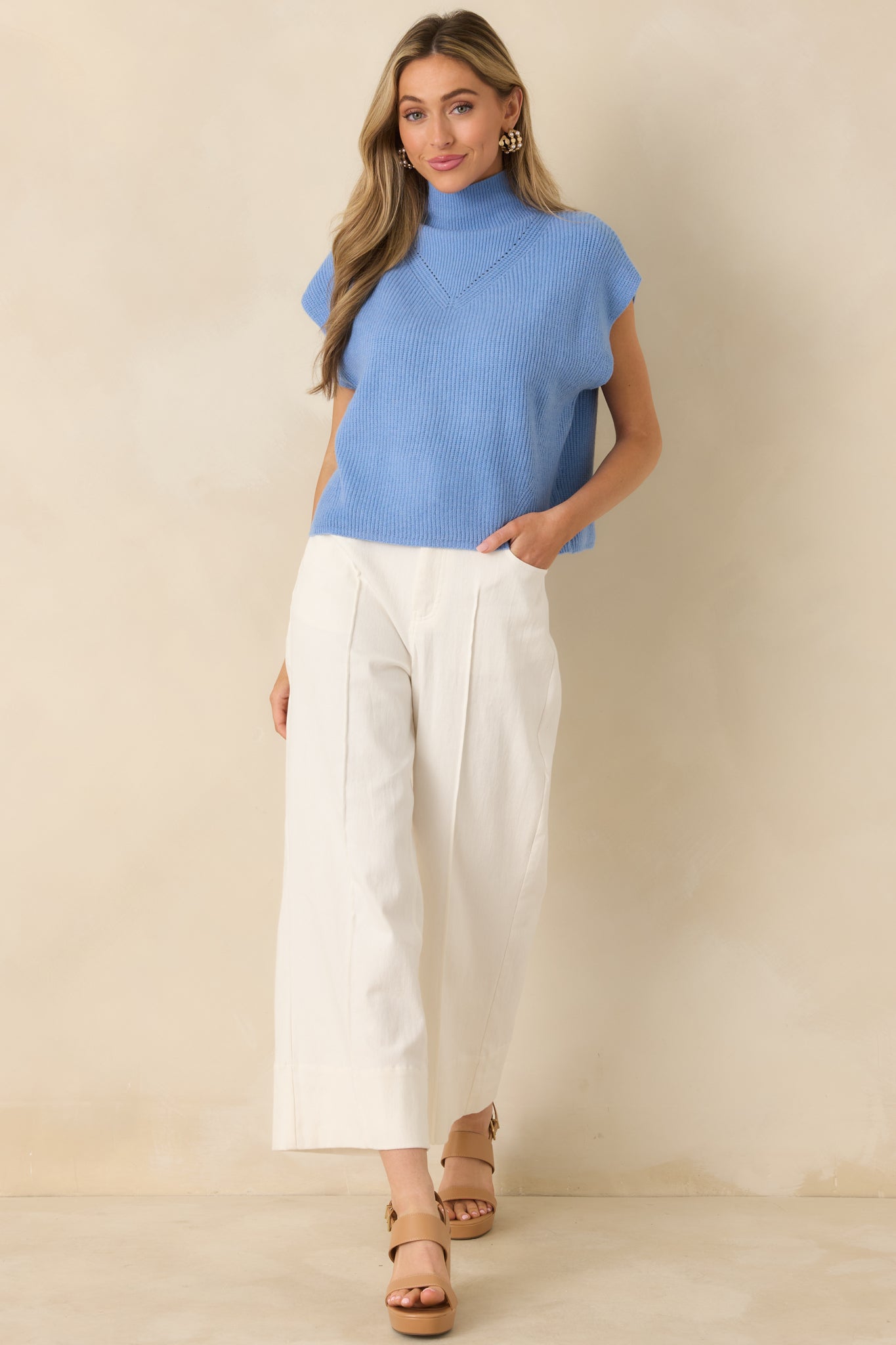 Blue ribbed knit sweater with a mock neckline, cap sleeves, and a relaxed fit for a polished, minimal silhouette.