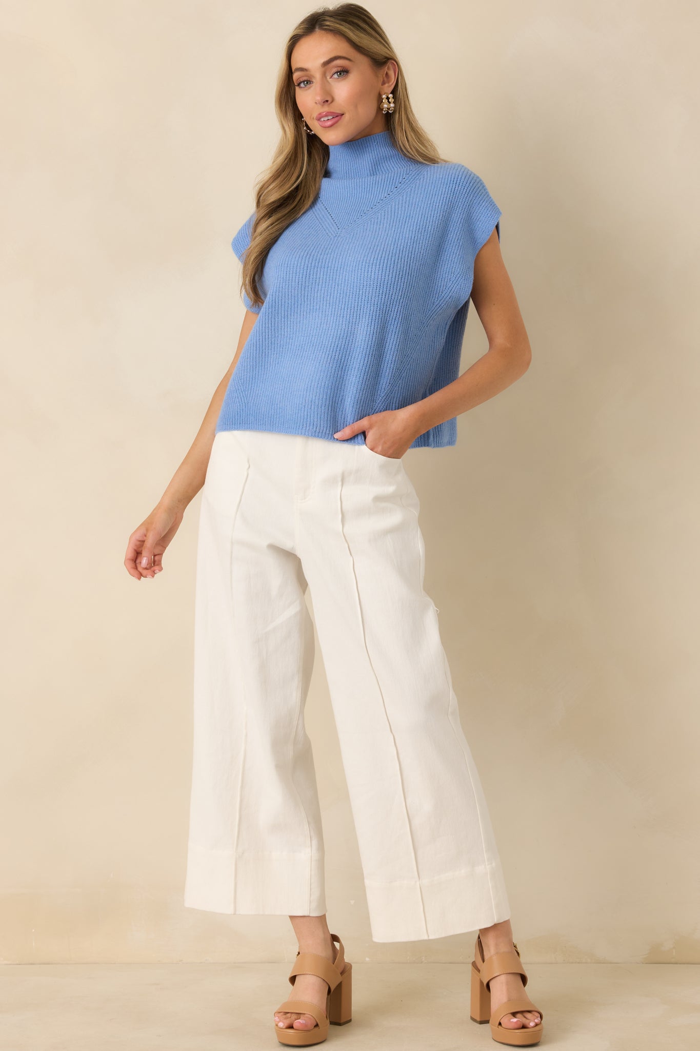 Blue ribbed knit sweater with a mock neckline, cap sleeves, and a relaxed silhouette flowing naturally to a clean hem.