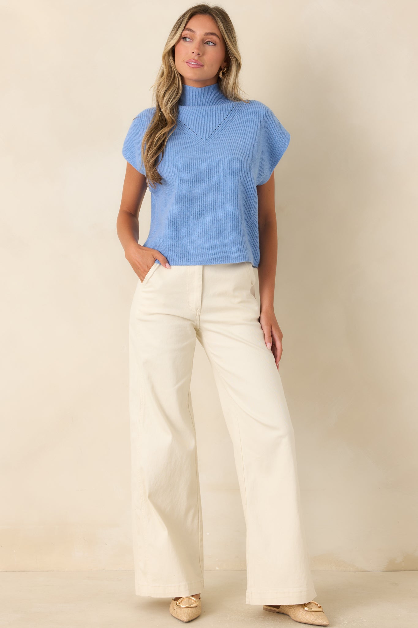 Blue ribbed knit top featuring a mock neckline, cap sleeves, relaxed fit, and subtle chest detailing for a polished finish.