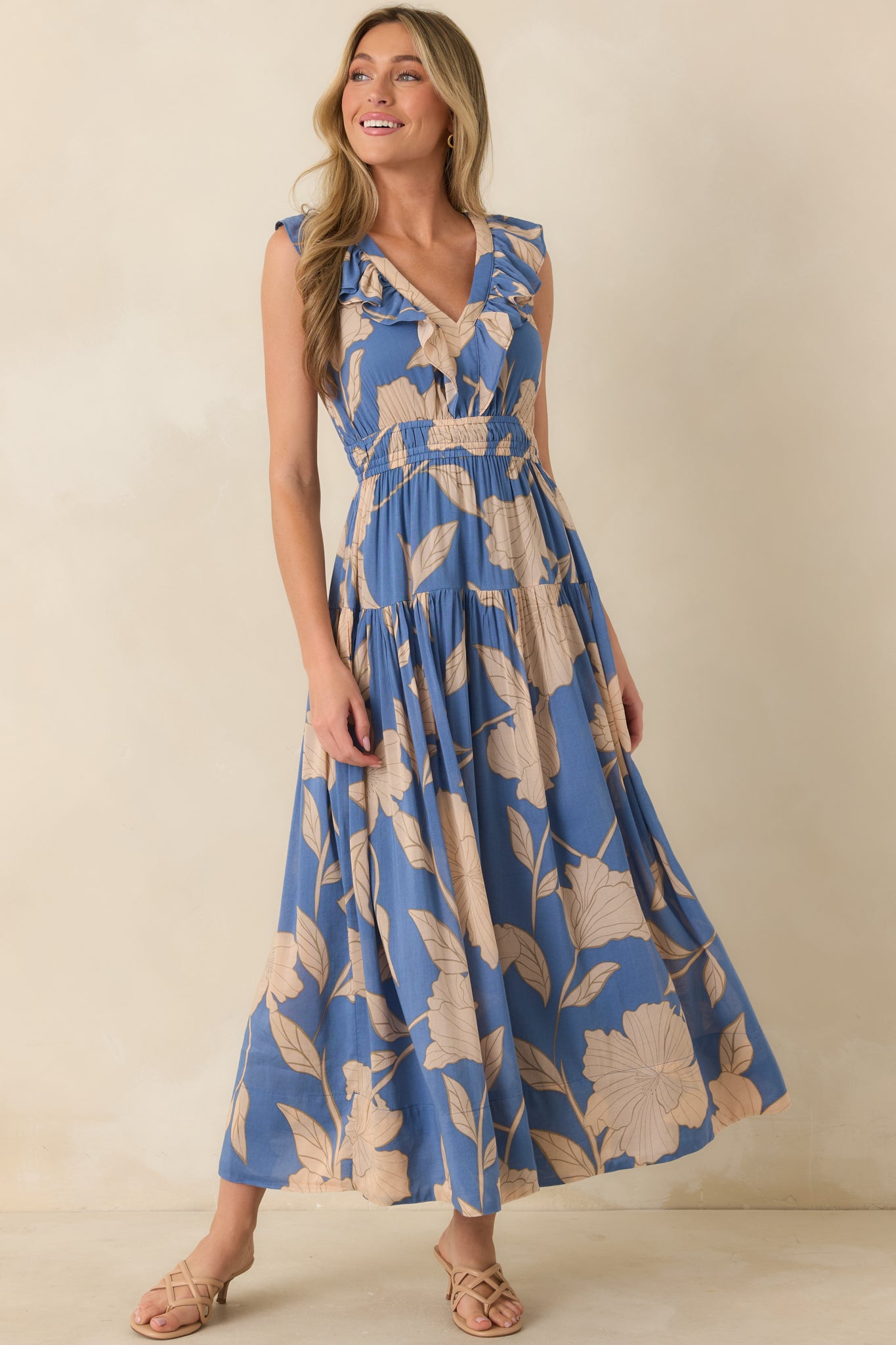 Blue floral maxi dress showcasing a ruffled V-neckline, smocked elastic waistband, and graceful movement throughout the lightweight fabric.