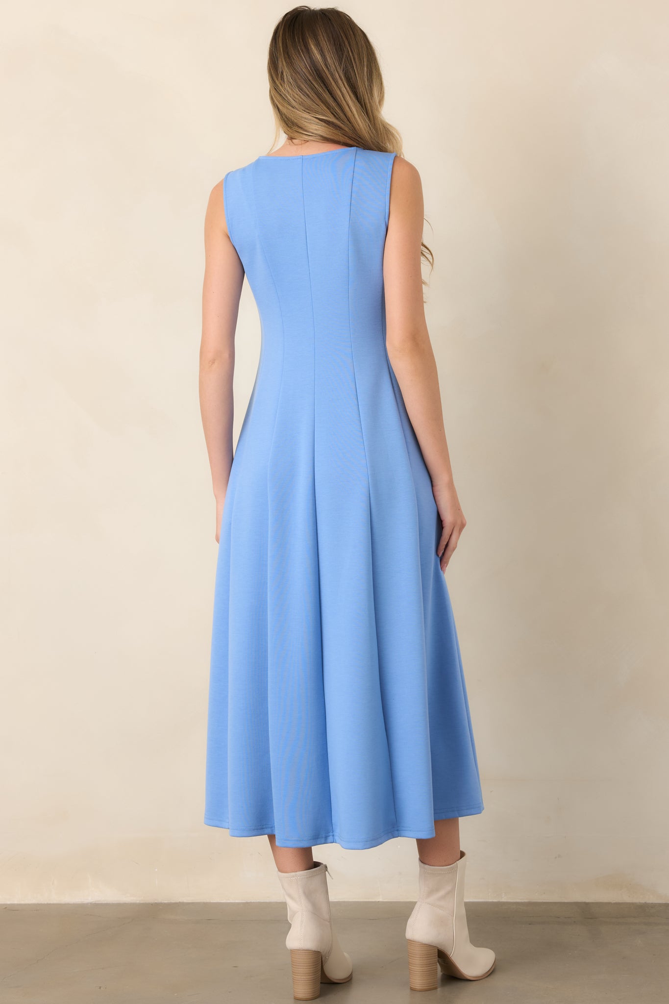 Rear view of the blue midi dress showcasing its sleeveless silhouette, smooth seamed panels, and flowing drape through the skirt.