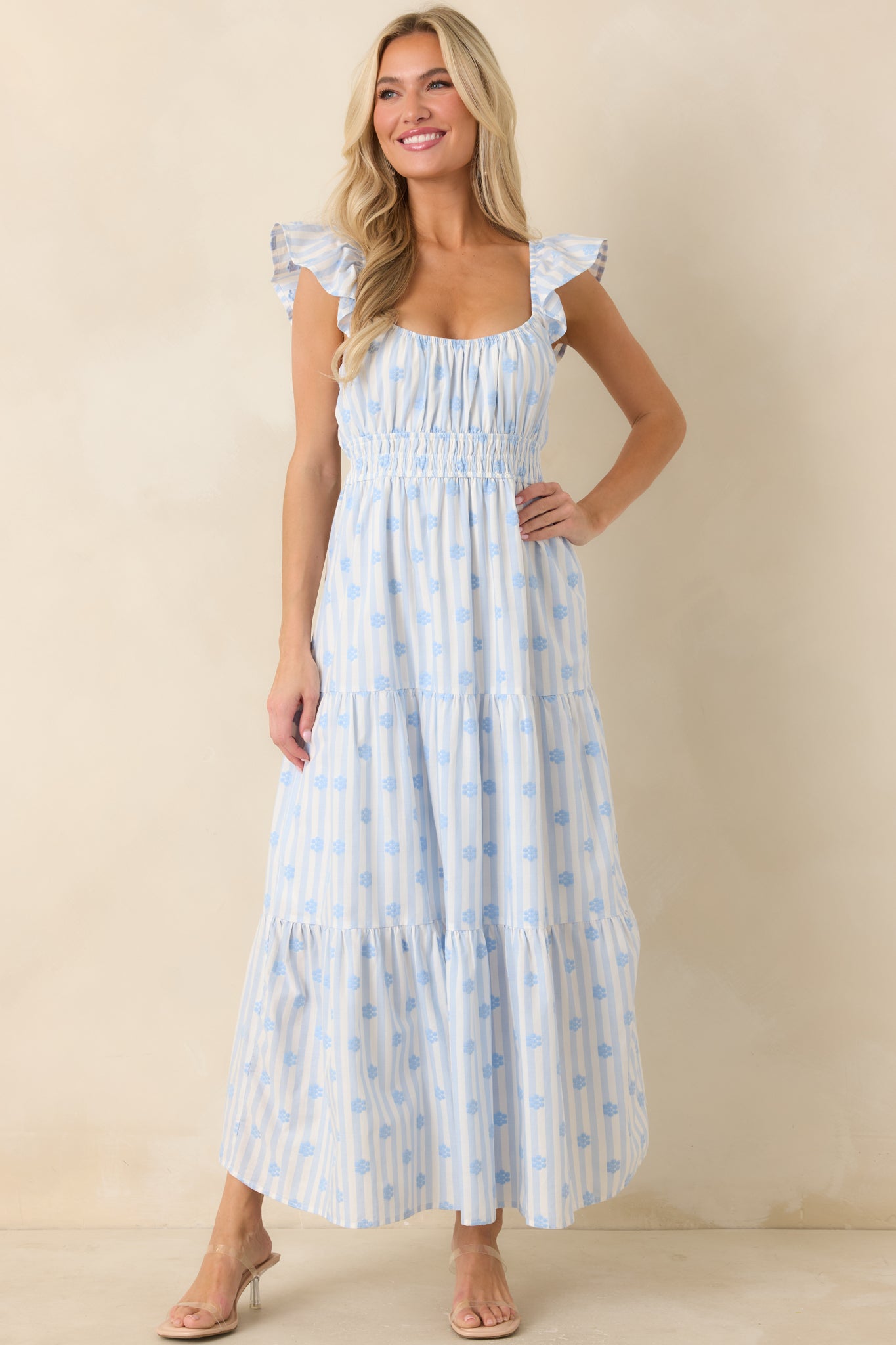 Blue stripe floral maxi dress featuring embroidered floral detailing, flutter sleeves, a gathered neckline, smocked waistband, and a flowing tiered silhouette.