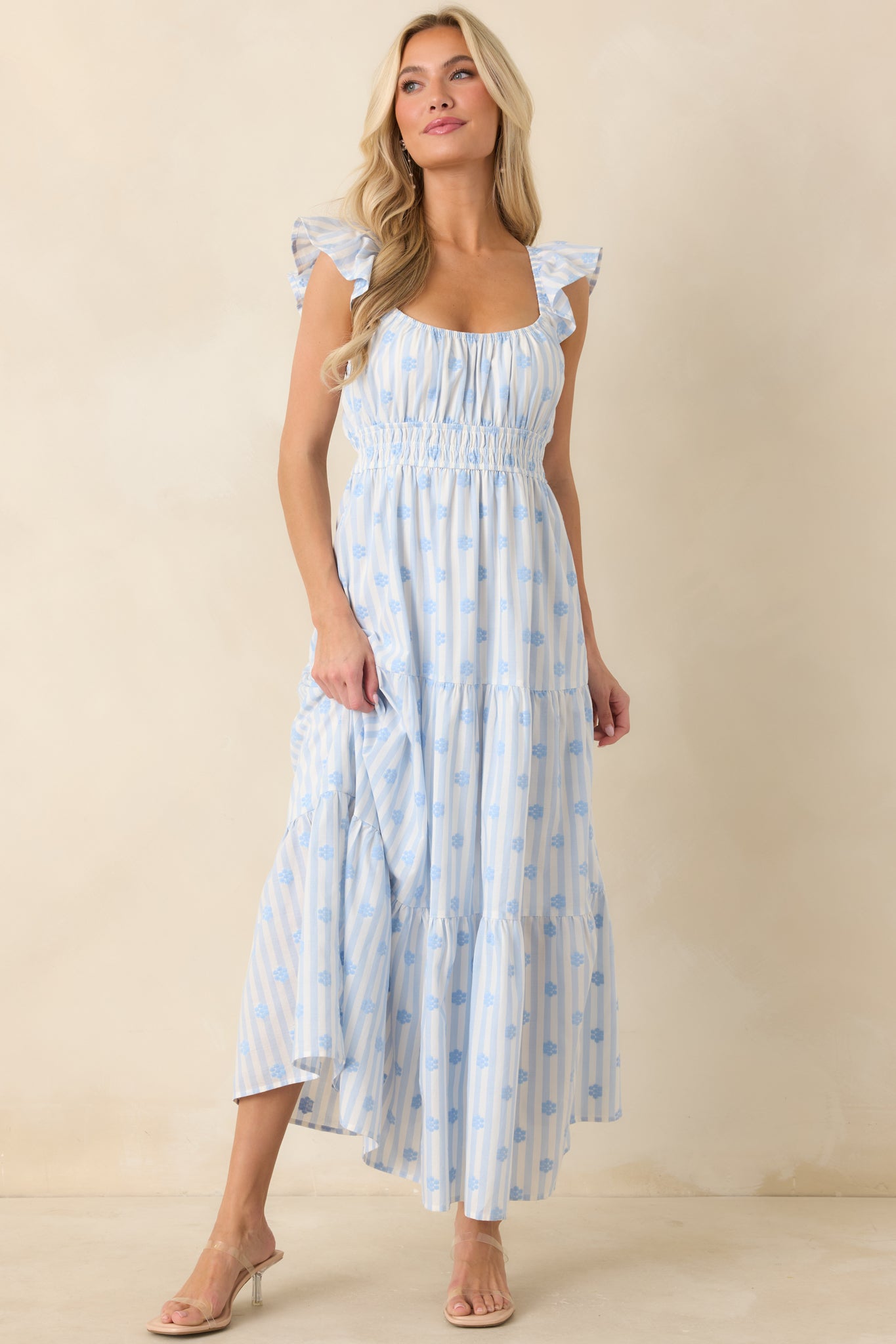 Blue stripe floral dress with a gathered neckline, airy flutter sleeves, elasticized waist, and graceful flowy maxi length.