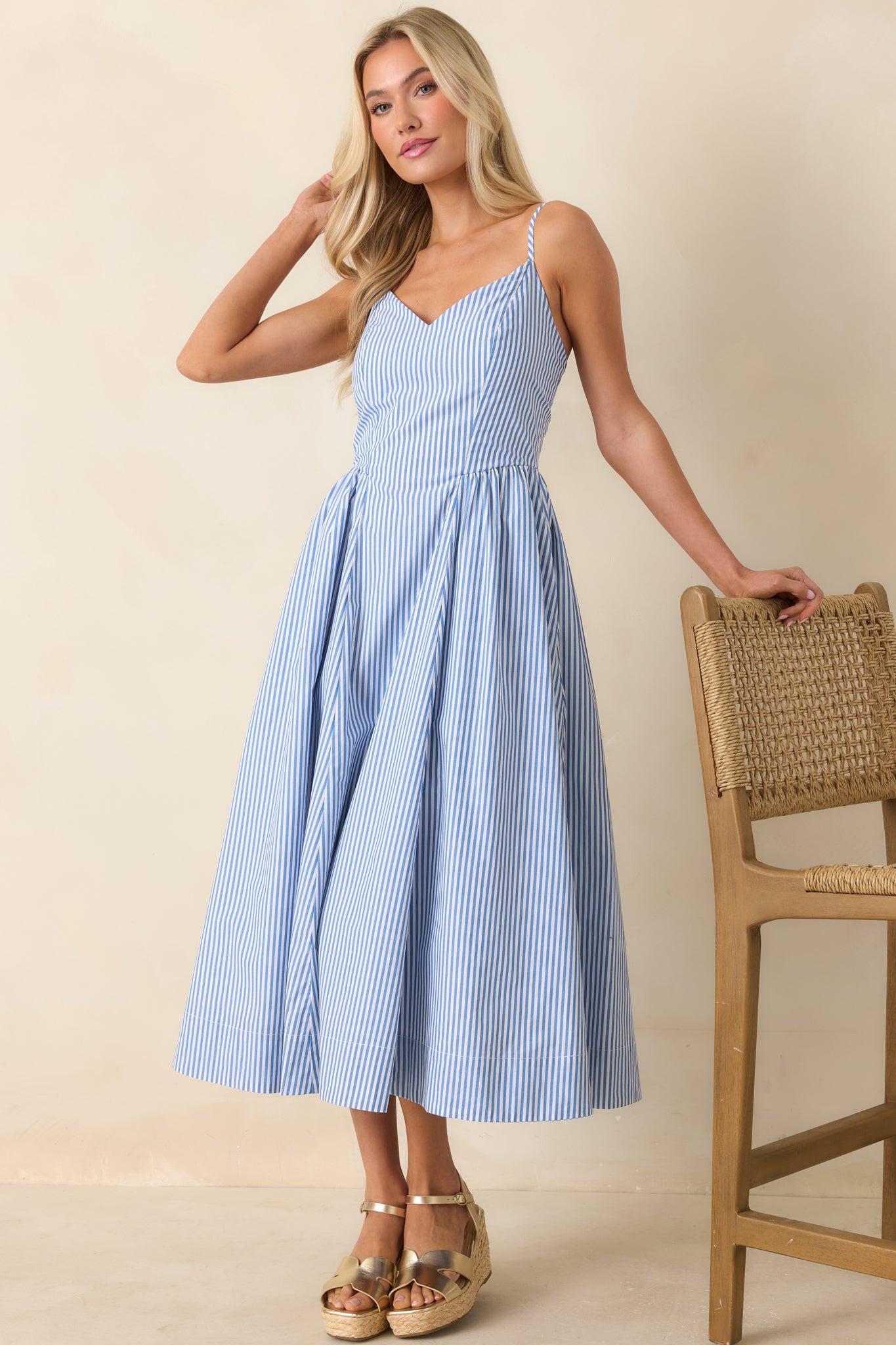 Blue striped midi dress with fitted bodice, airy skirt, and soft vertical stripe pattern.