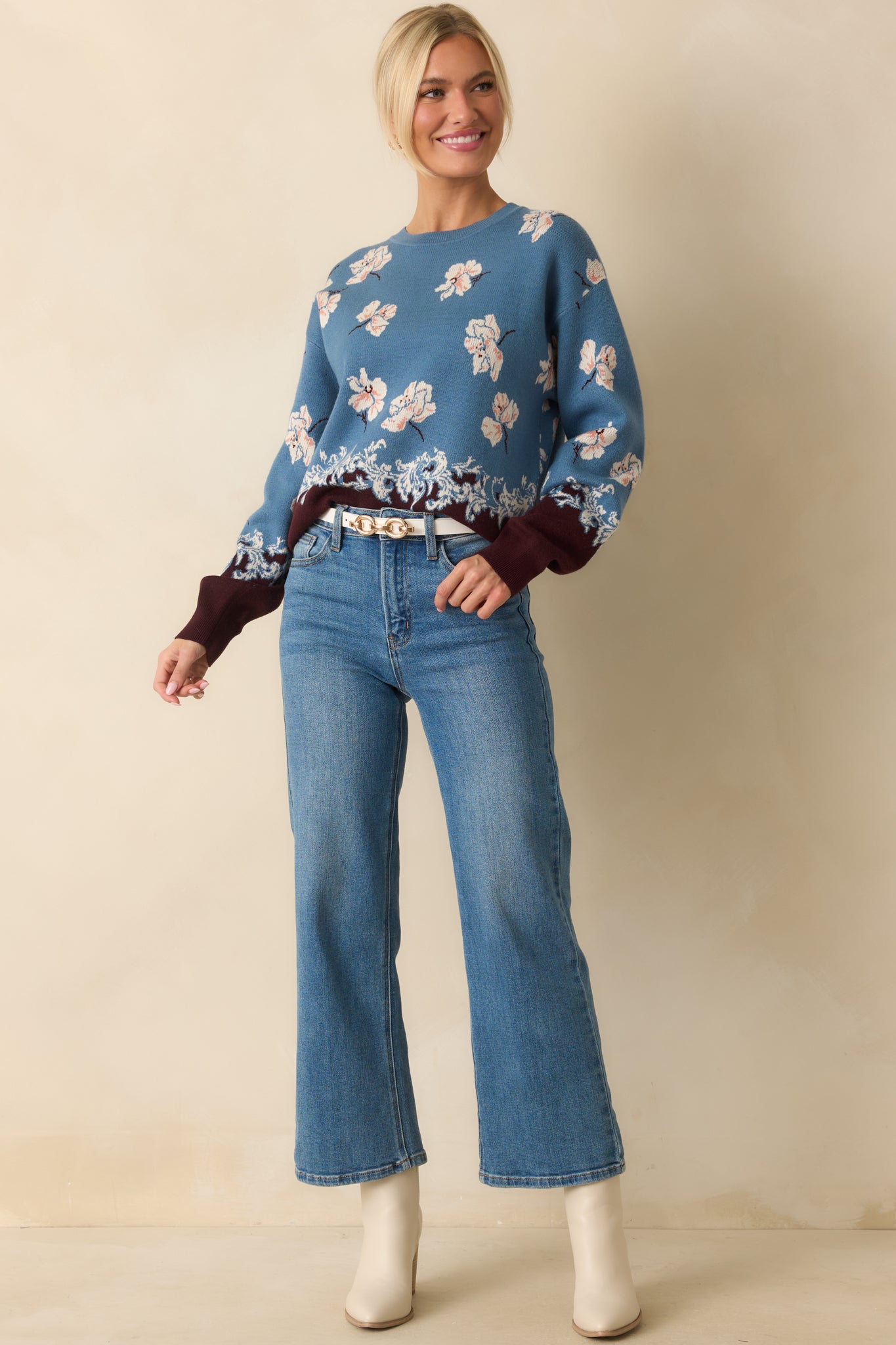 Relaxed-fit blue sweater with ivory jacquard design, ribbed cuffs, and ornate border detail along the bottom edge.