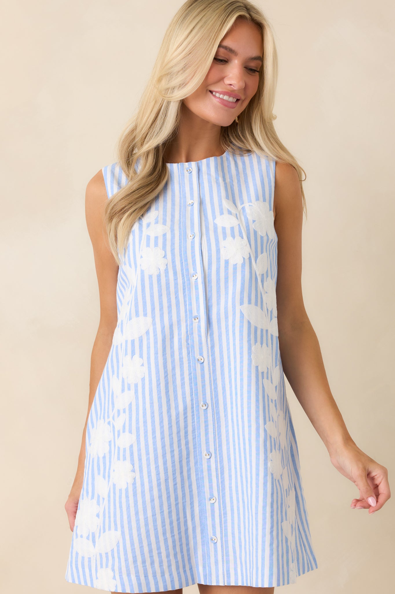 Close view of the blue and white vertical stripe pattern, tonal floral details, and button-front design.