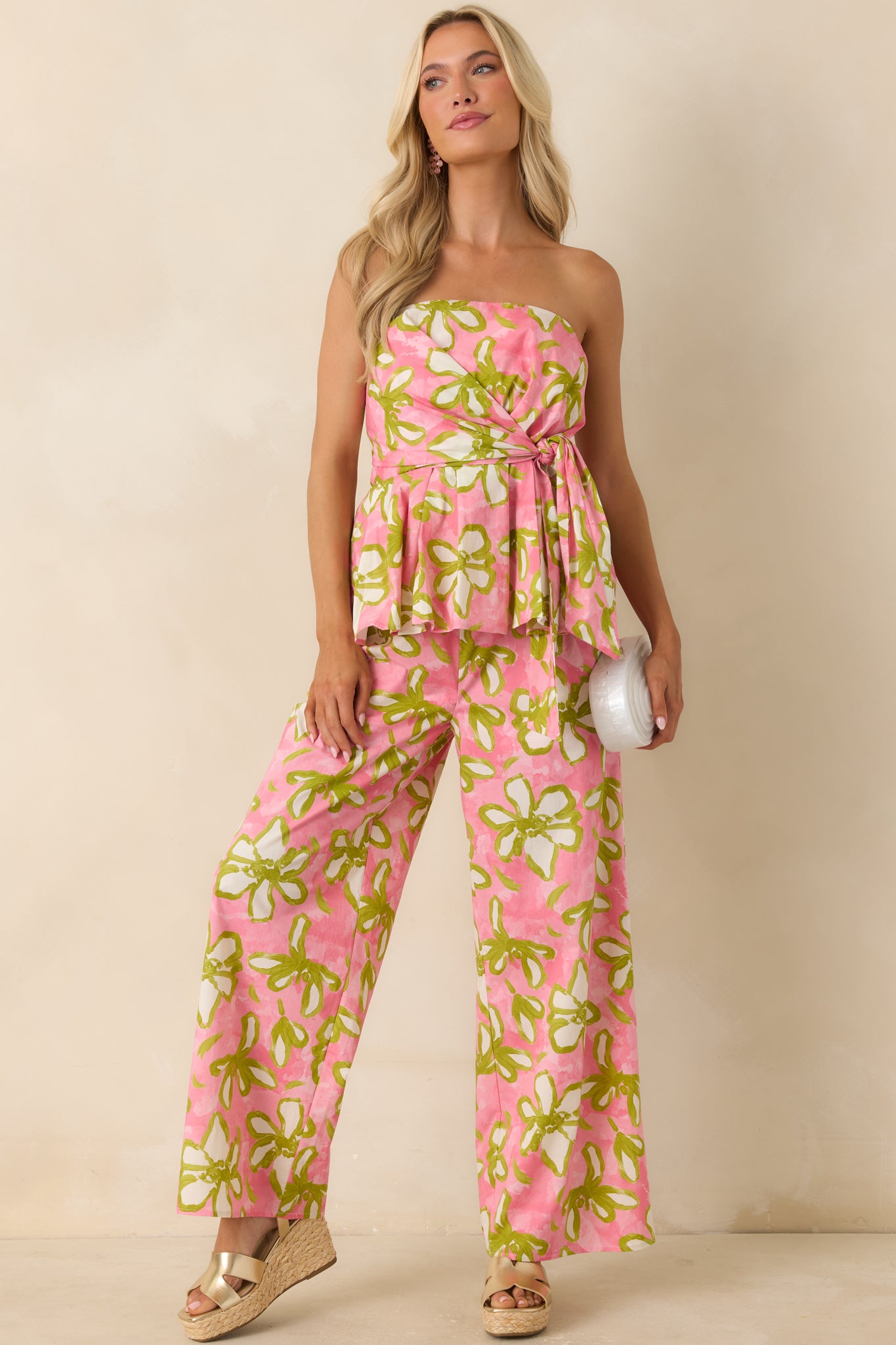 Bold floral print pants in pink, olive green, and ivory featuring a relaxed wide-leg silhouette and elastic waistband with adjustable drawstring.