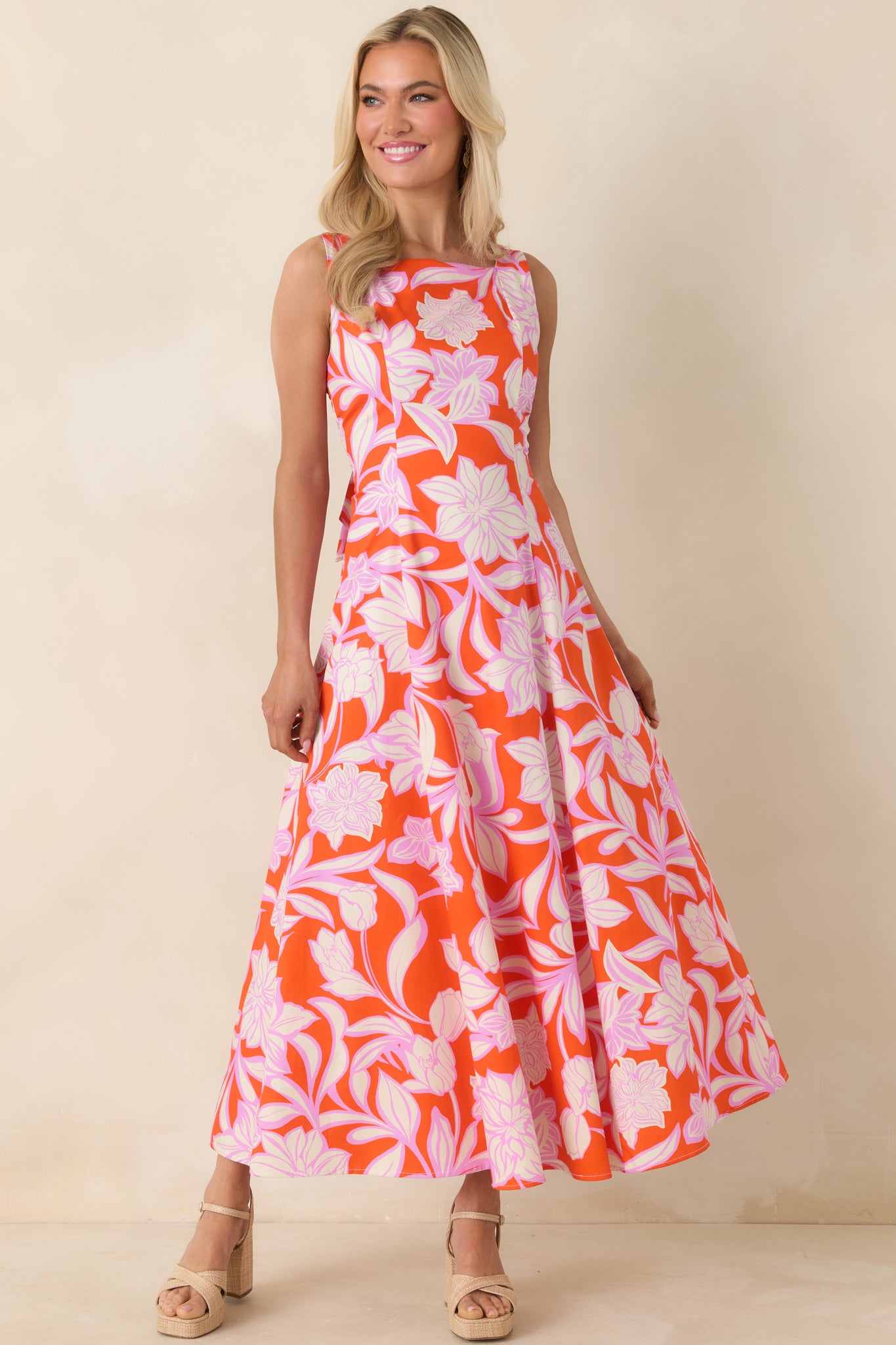 Bold orange floral maxi dress with airy skirt and elegant sleeveless design.