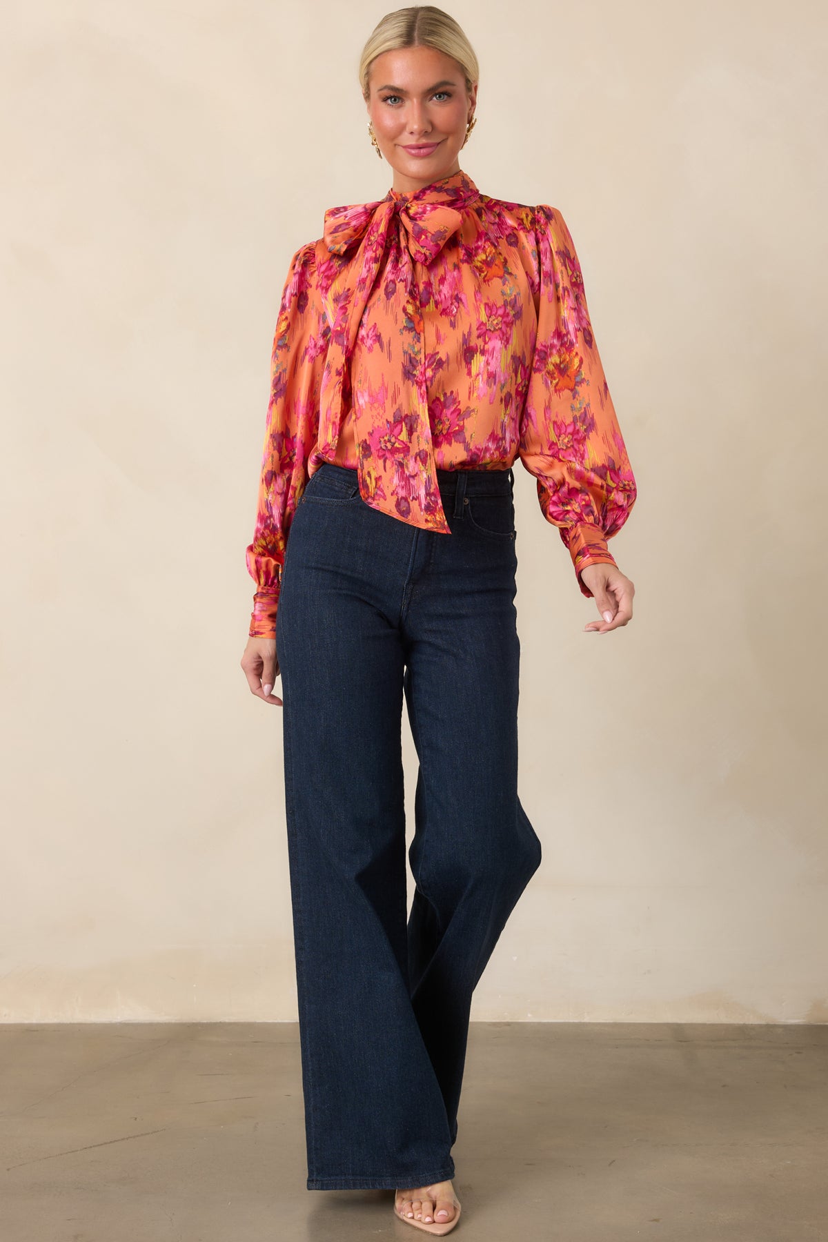Bold satin blouse showcasing its elegant drape, dramatic tie neckline, gently gathered shoulders, and voluminous balloon sleeves with buttoned cuffs.