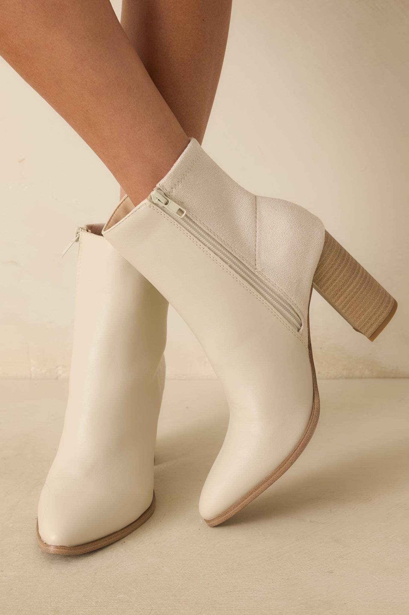 A close-up of the boots showing a smooth faux leather front, faux suede back, and stitching details near the heel and zipper.