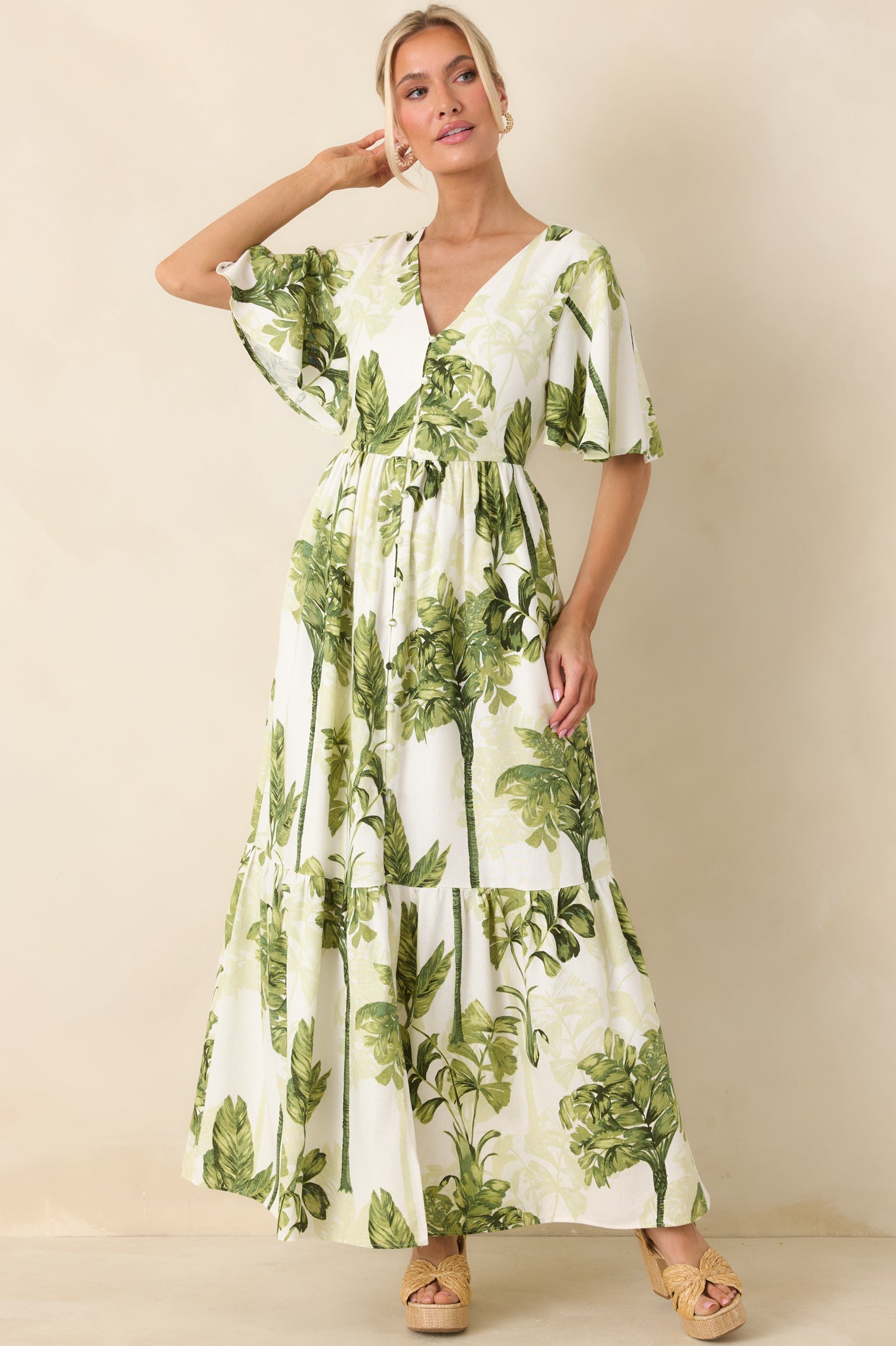 Green and ivory botanical print maxi dress with structured bodice, V-neck front, and voluminous tiered skirt for a balanced silhouette.