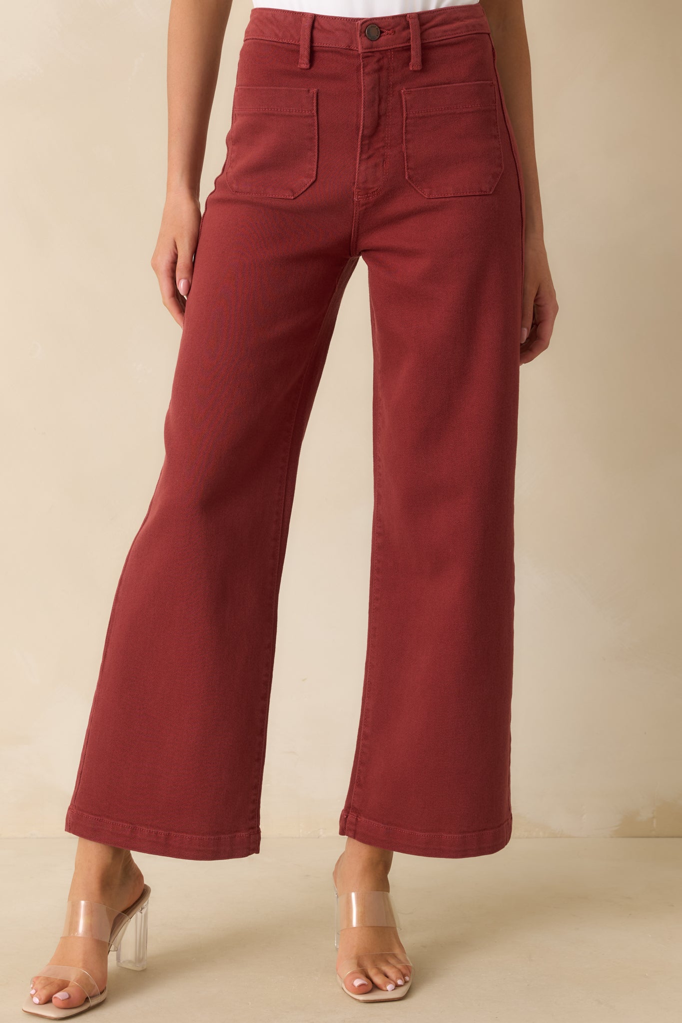 High-rise brick red denim jeans with a relaxed wide leg fit and classic patch pockets.
