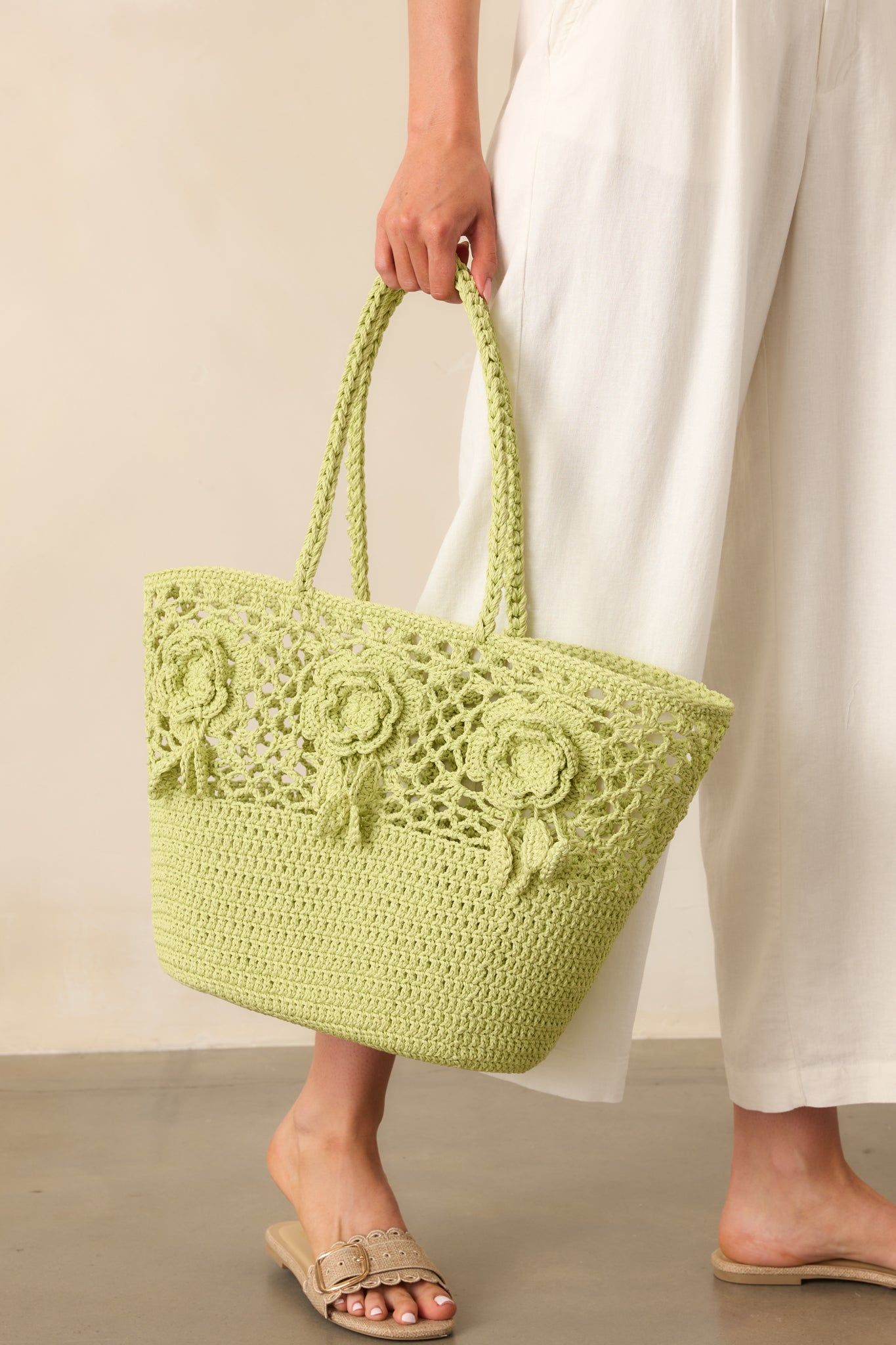 A full-length image of the bright green woven tote bag showcasing the open-tote design and three 3D floral appliqués on the front.