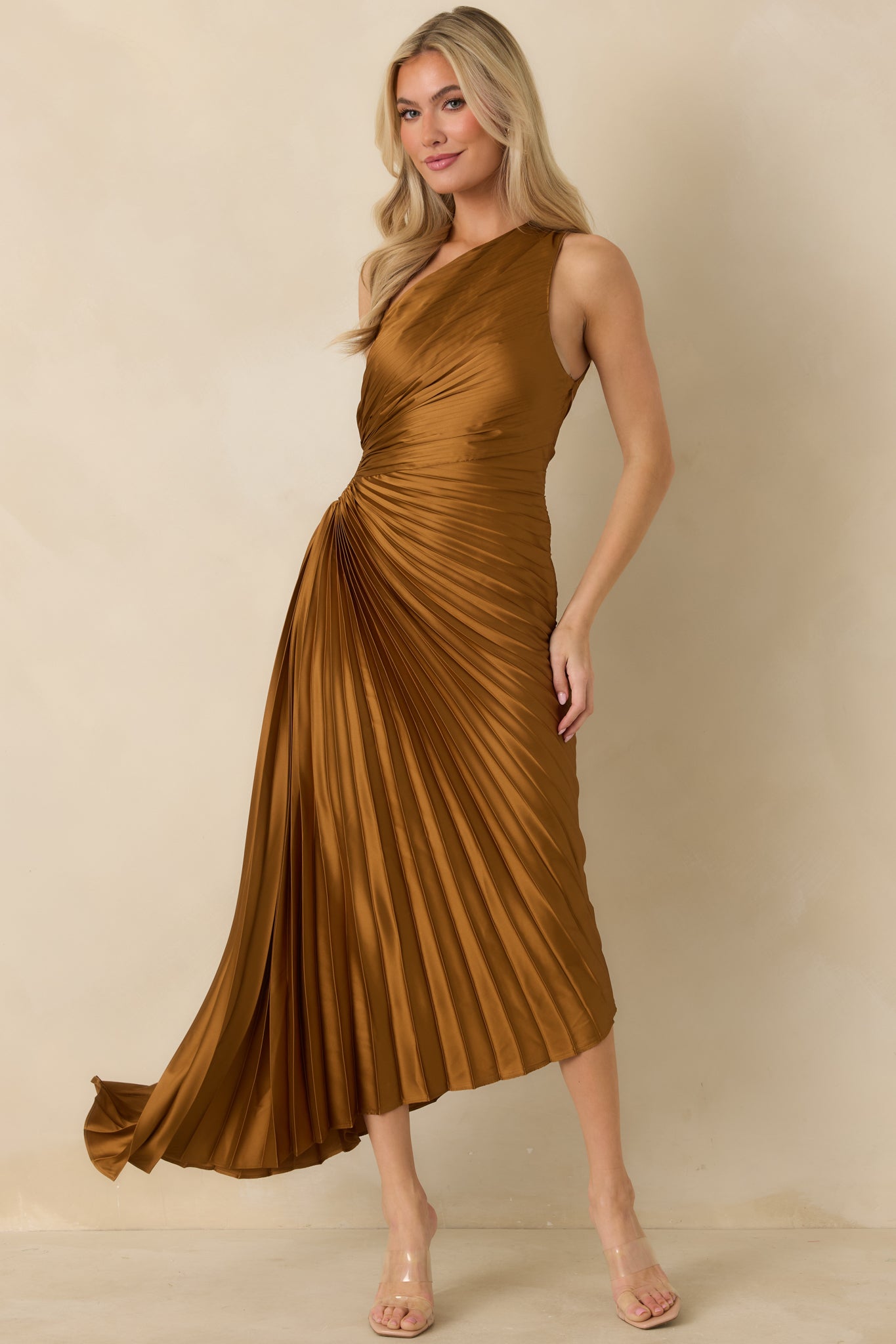 Front view of bronze pleated maxi dress showcasing asymmetric hemline and elegant drape of the skirt.