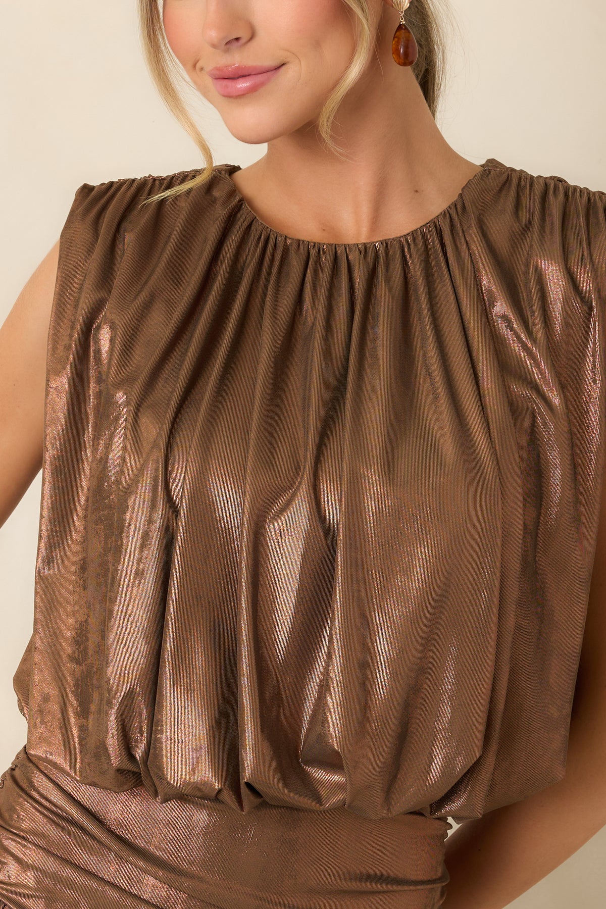 Close-up of the bronze top’s gathered round neckline and softly textured fabric with a subtle coppery sheen.