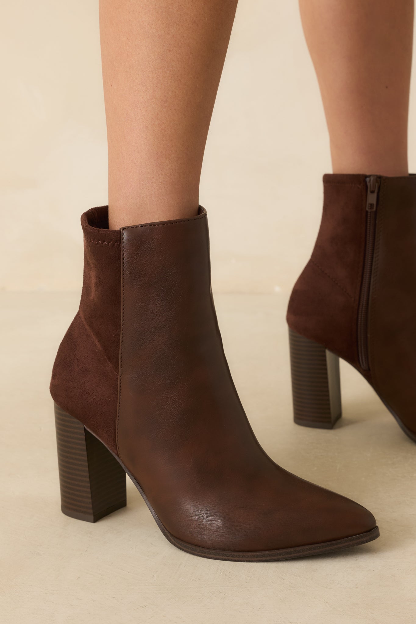 Close crop showing tonal faux suede back panel and inner side zipper of brown ankle boot.