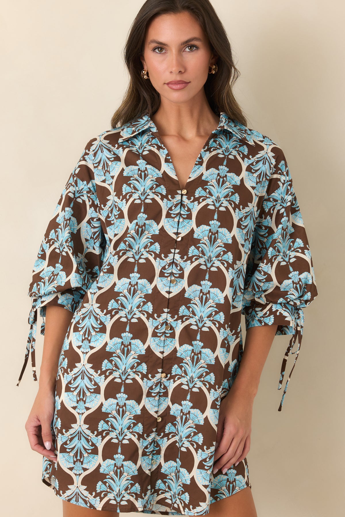 Brown and blue floral mini dress with a relaxed silhouette, functional side pockets, and a curved hem.
