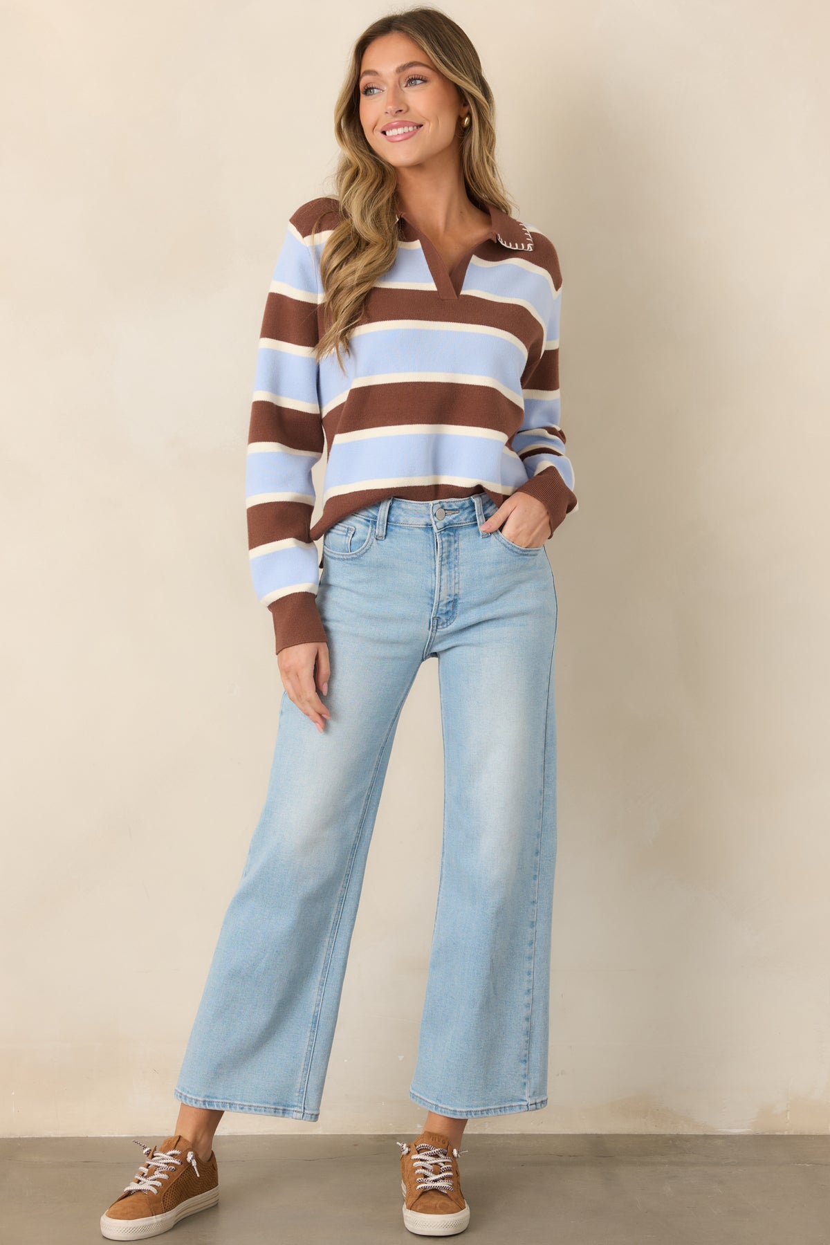 Relaxed color-blocked sweater with bold brown, blue, and white stripes, a pointed brown collar, V-shaped neckline, and full-length sleeves with ribbed cuffs.
