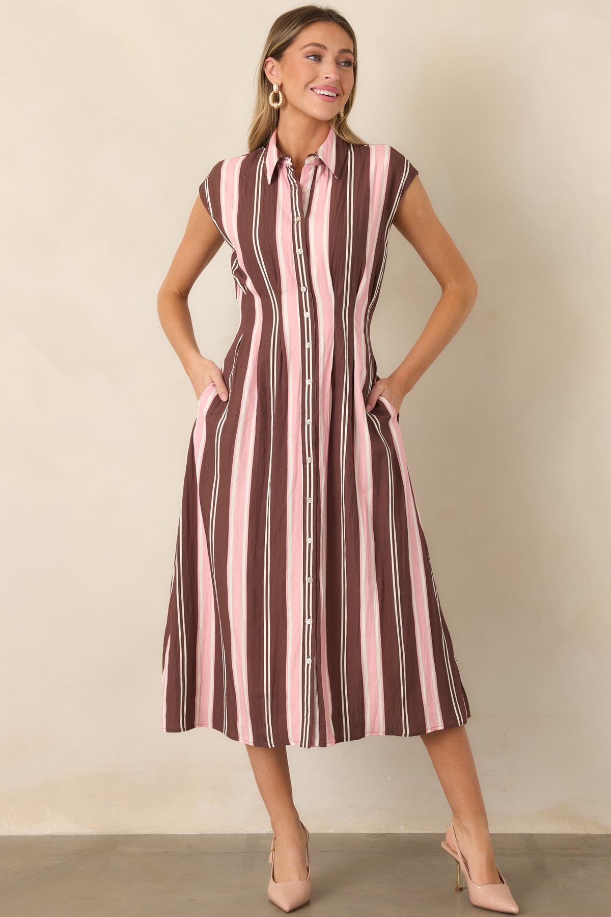 Classic button-front midi dress in brown, blush pink, and ivory stripes, featuring a softly shaped waist, cap sleeves, and side pockets.