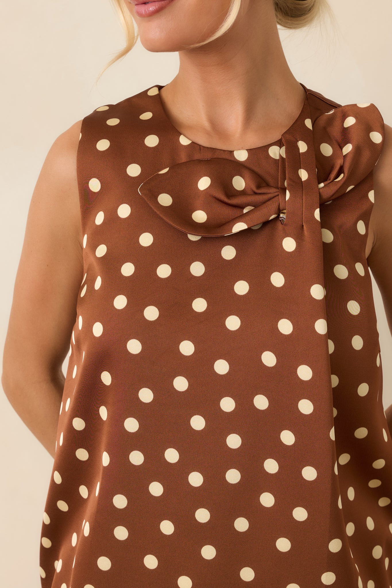 Close-up of the oversized bow neckline showcasing the rich brown fabric and cream polka dot pattern.