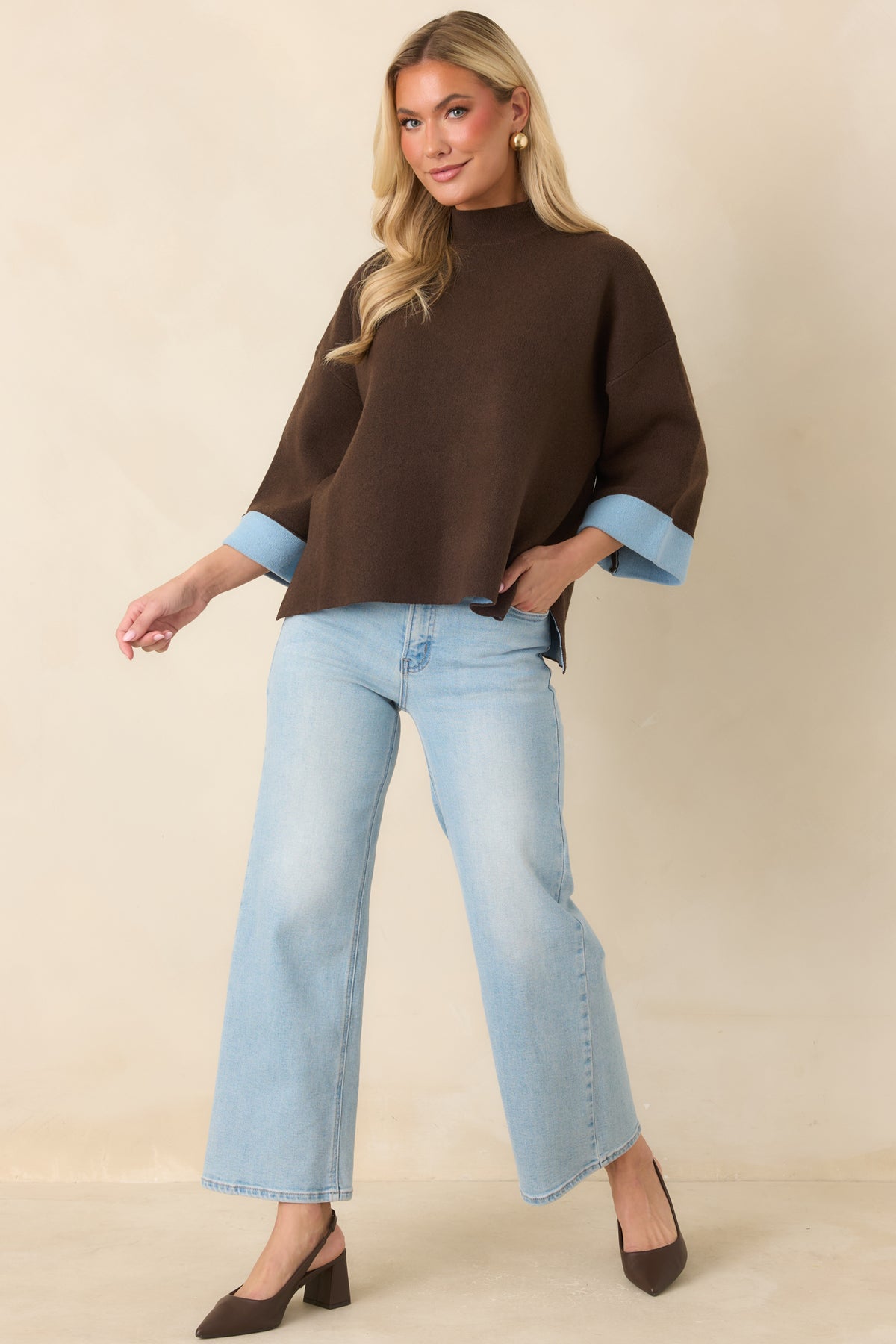 Boxy brown knit top with dropped shoulders, light blue folded cuffs, and an easy draped shape.