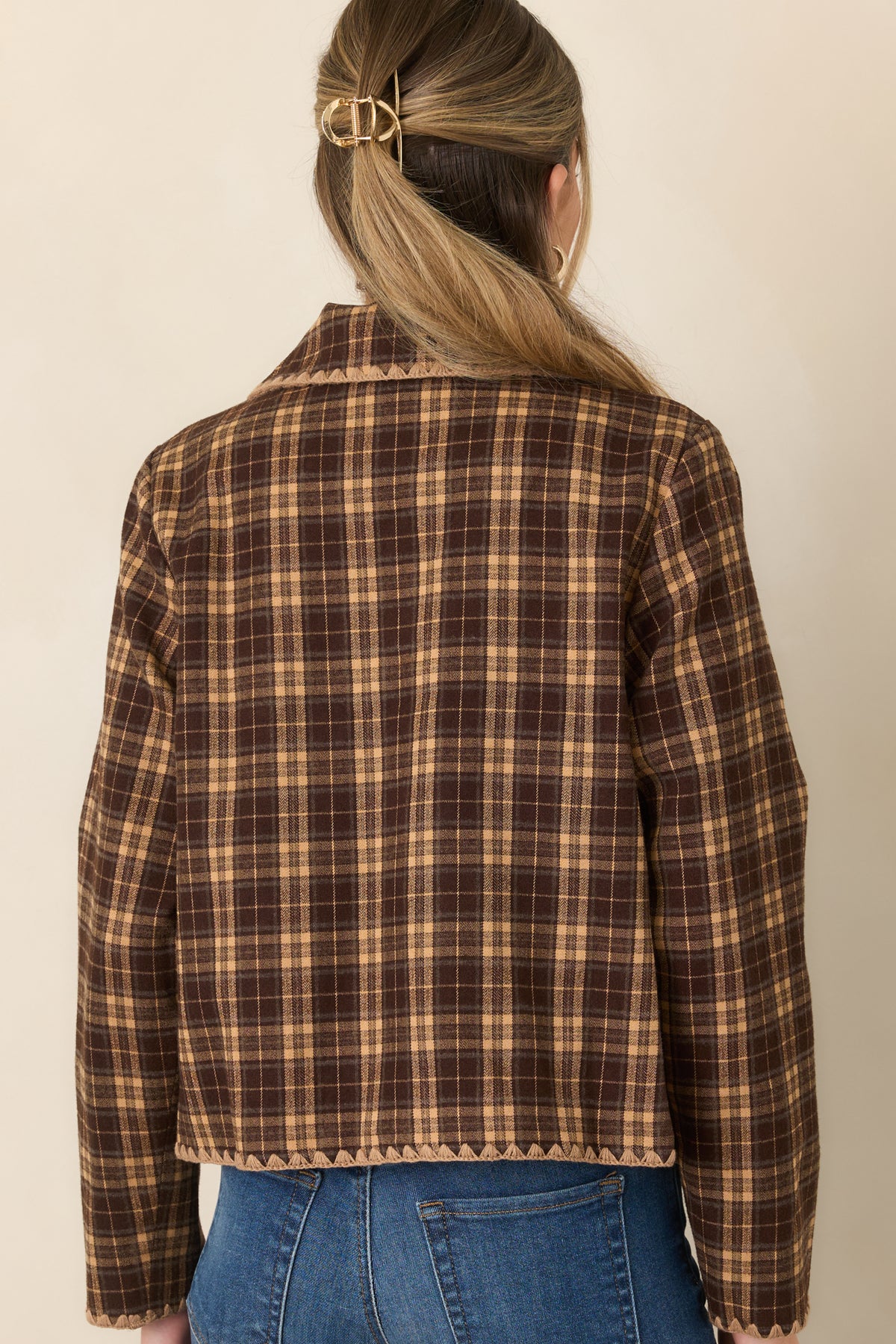 Rear of the brown and camel plaid jacket showing the structured boxy silhouette and scalloped contrast stitching along the hem.