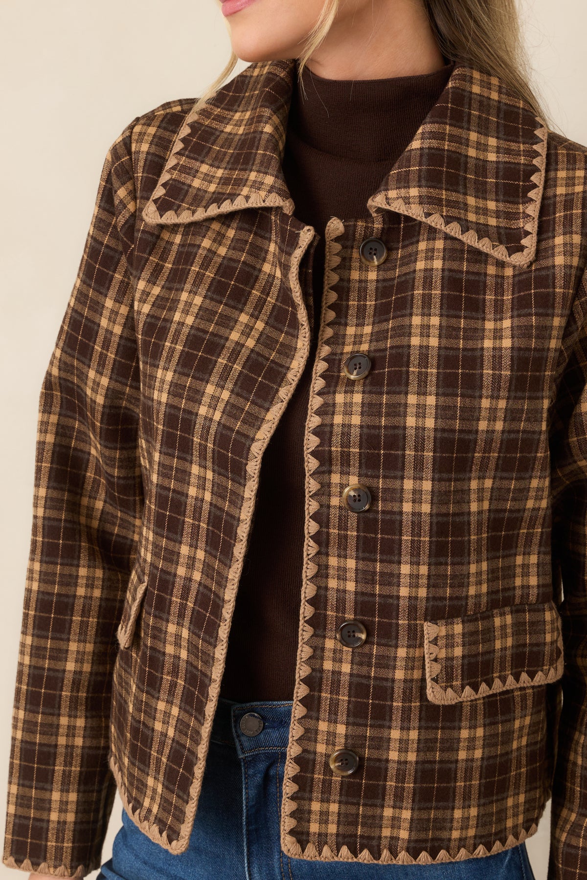 Brown and camel plaid jacket detail highlighting the scalloped contrast stitching and tonal buttons along the front.