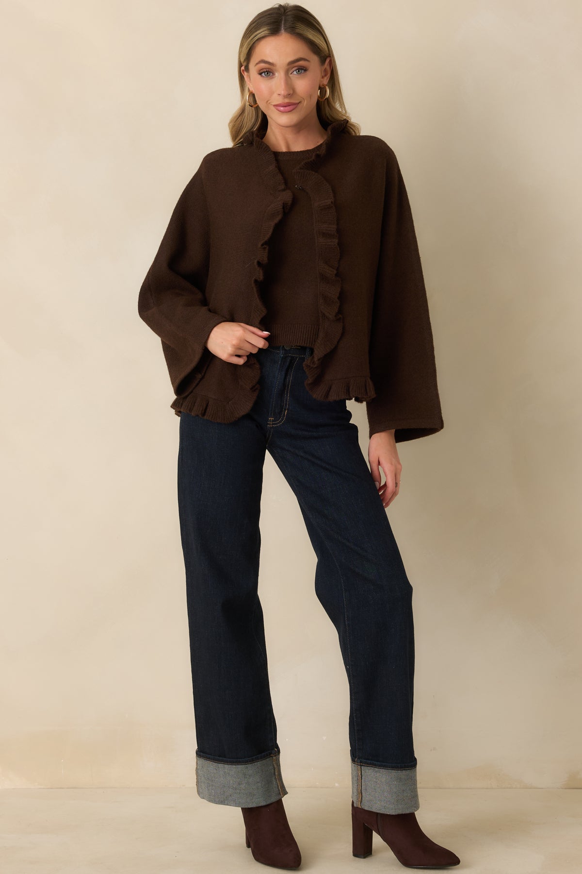 Brown cape-inspired cardigan with wide long sleeves and ruffle trim framing the neckline, front, and hem.