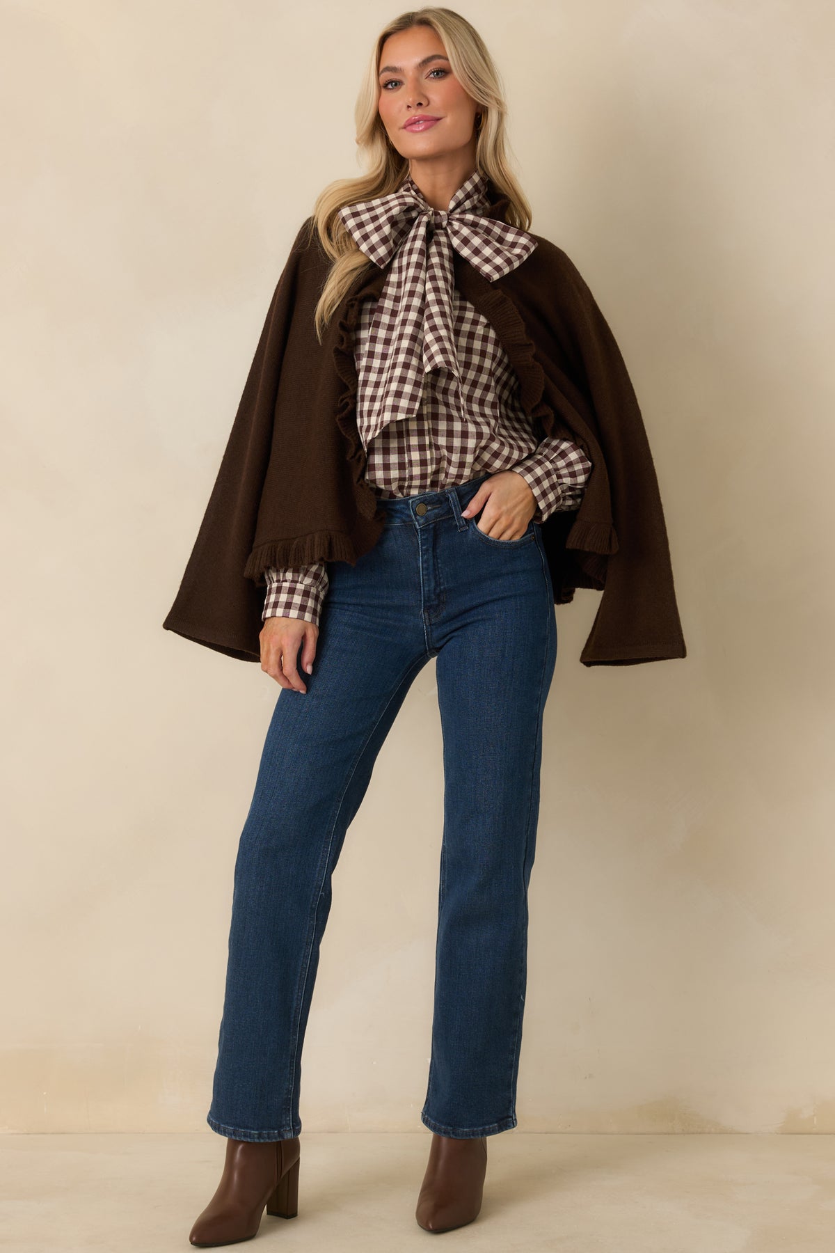 Brown cape-style knit cardigan with a loose open front, softly flared sleeves, and ruffle-trimmed hem.